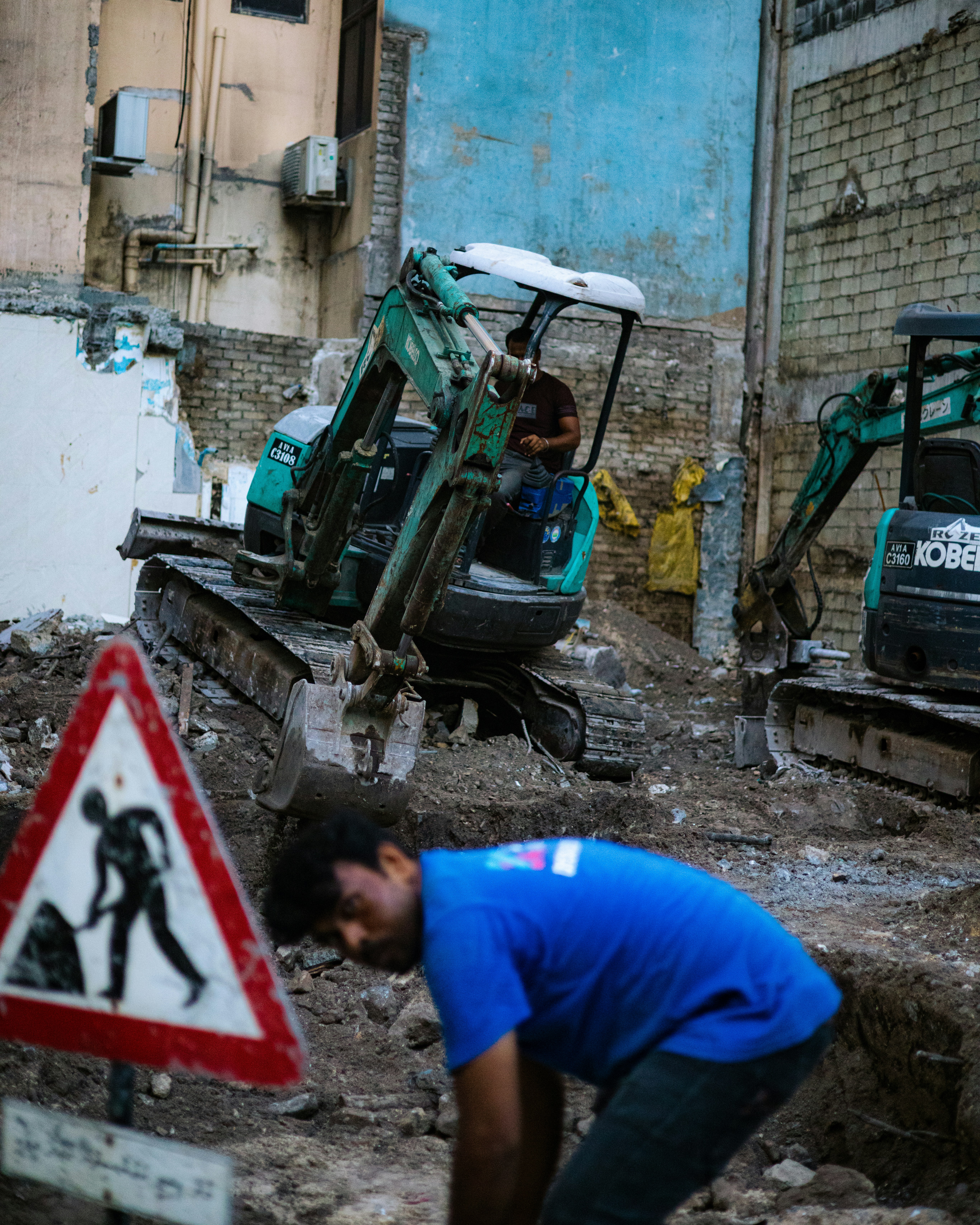 Construction site with excavators and worker.