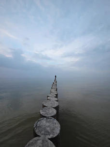 Lone figure stands on wooden posts over water