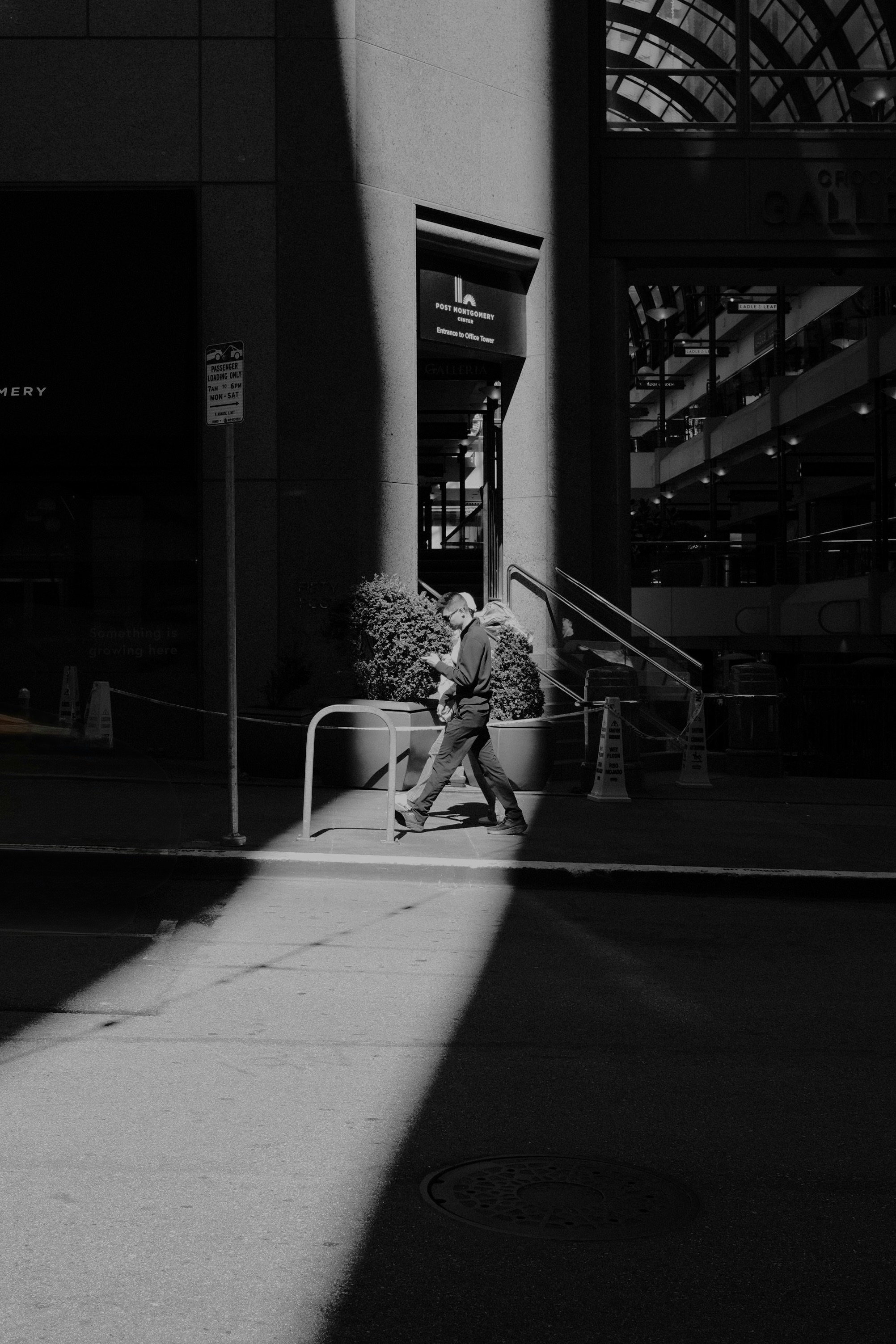 Una persona pasa junto a la entrada de un edificio con sombras dramáticas.