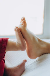 Two pairs of feet touching near a window