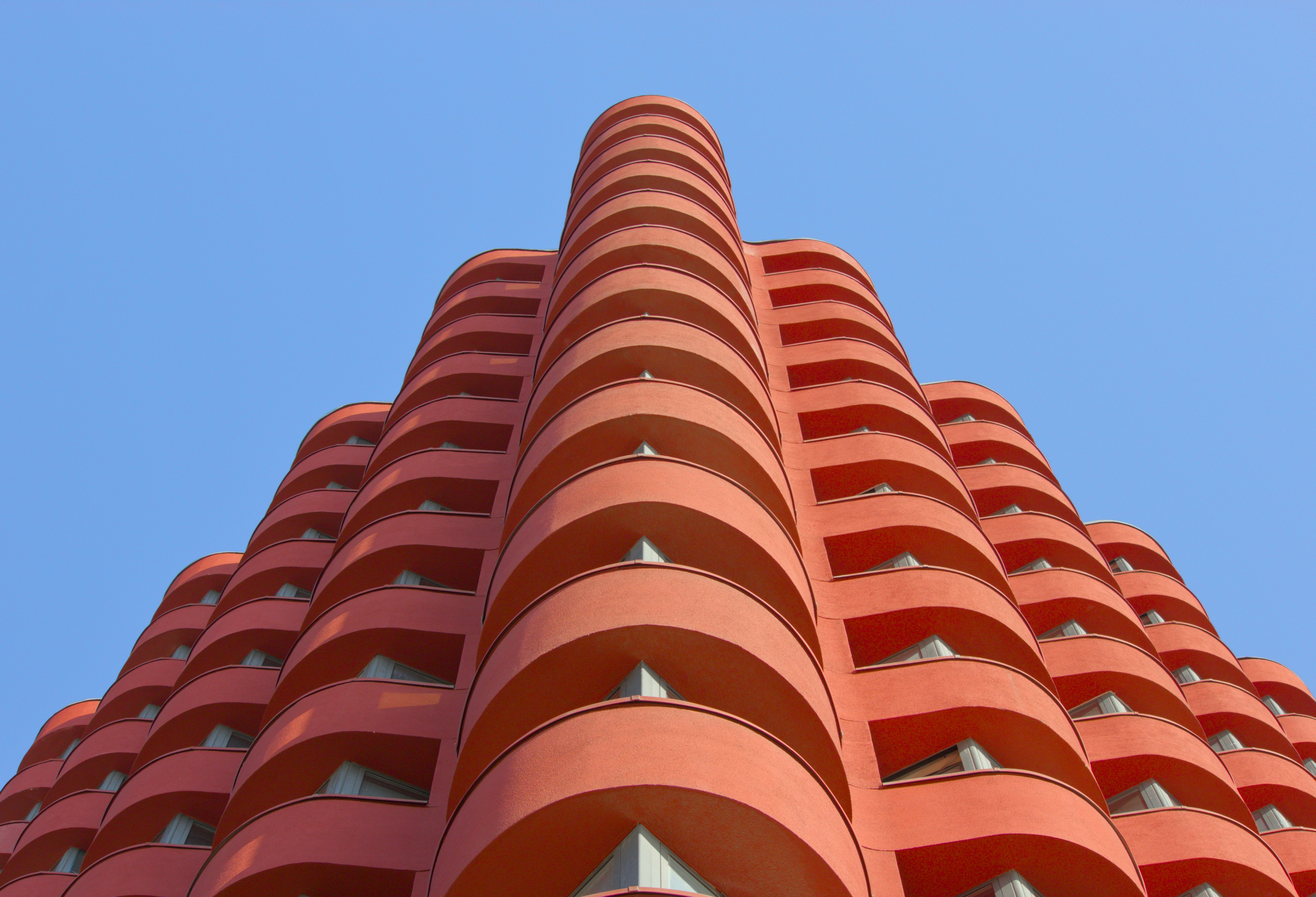 Modern orange building with curved balconies against blue sky