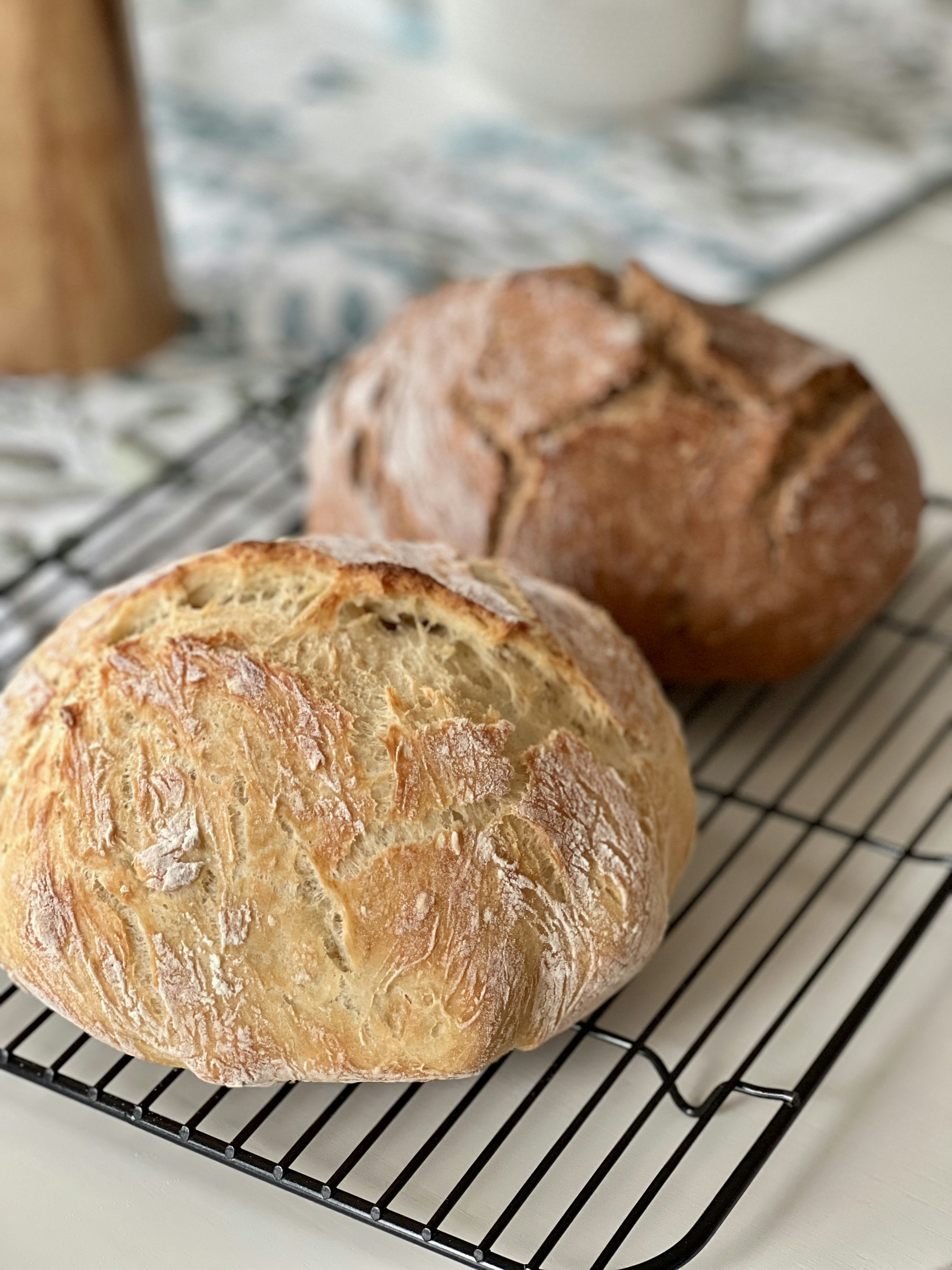 Two loaves of crusty artisan bread on a cooling rack