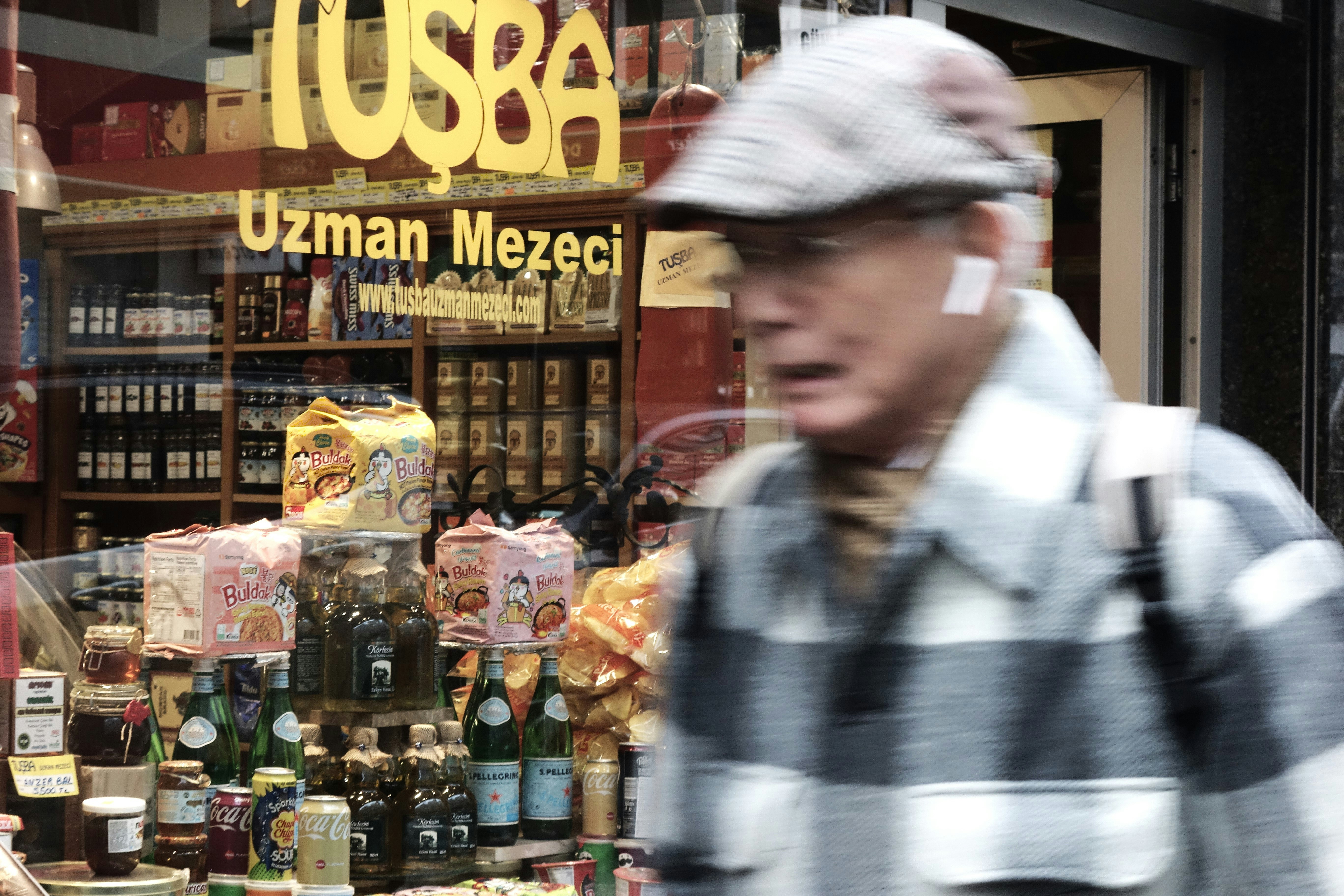 Man in plaid jacket walks past turkish store window