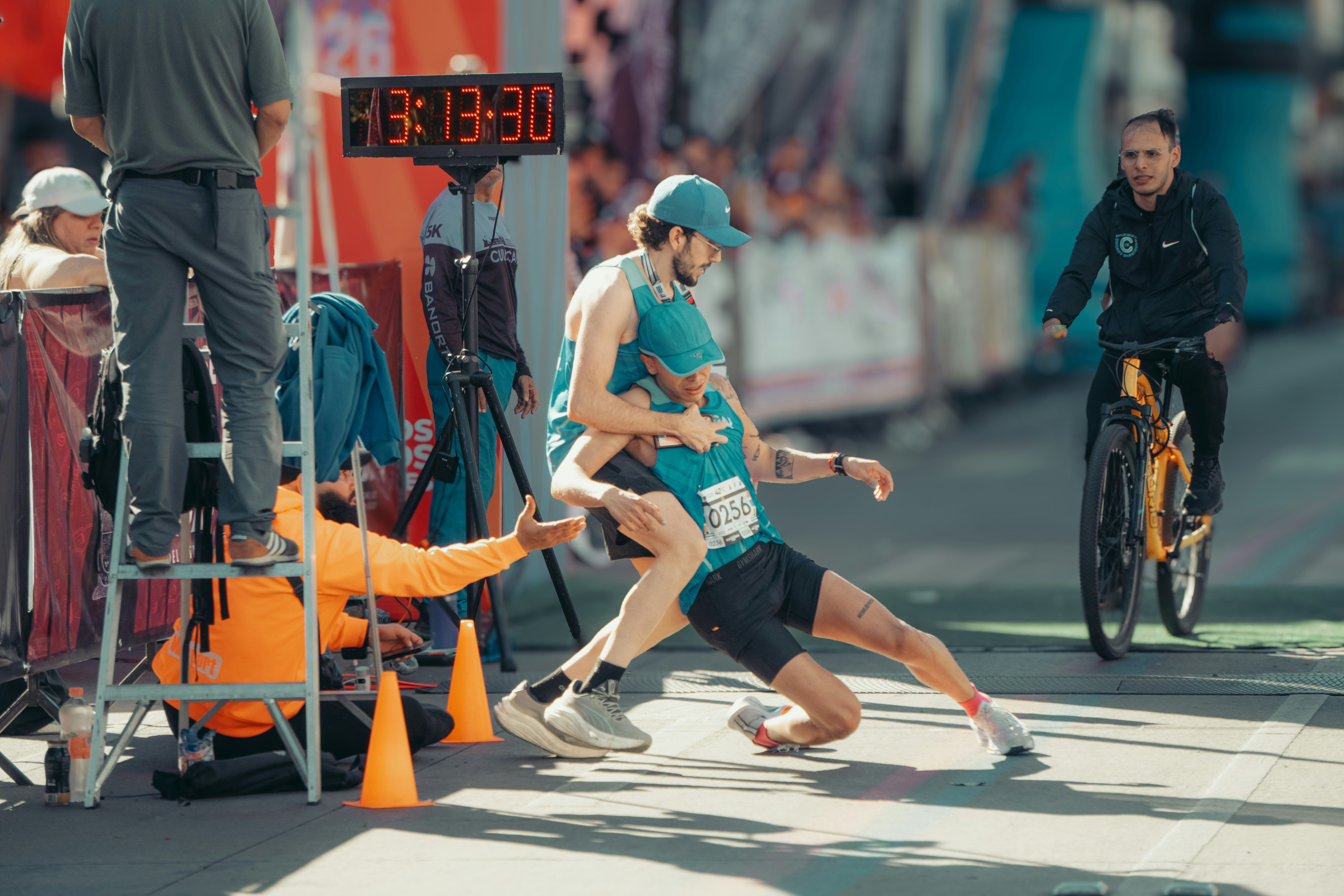 Runner collapses at finish line, helped by official.
