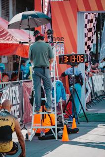 Man on ladder watches race clock at finish line