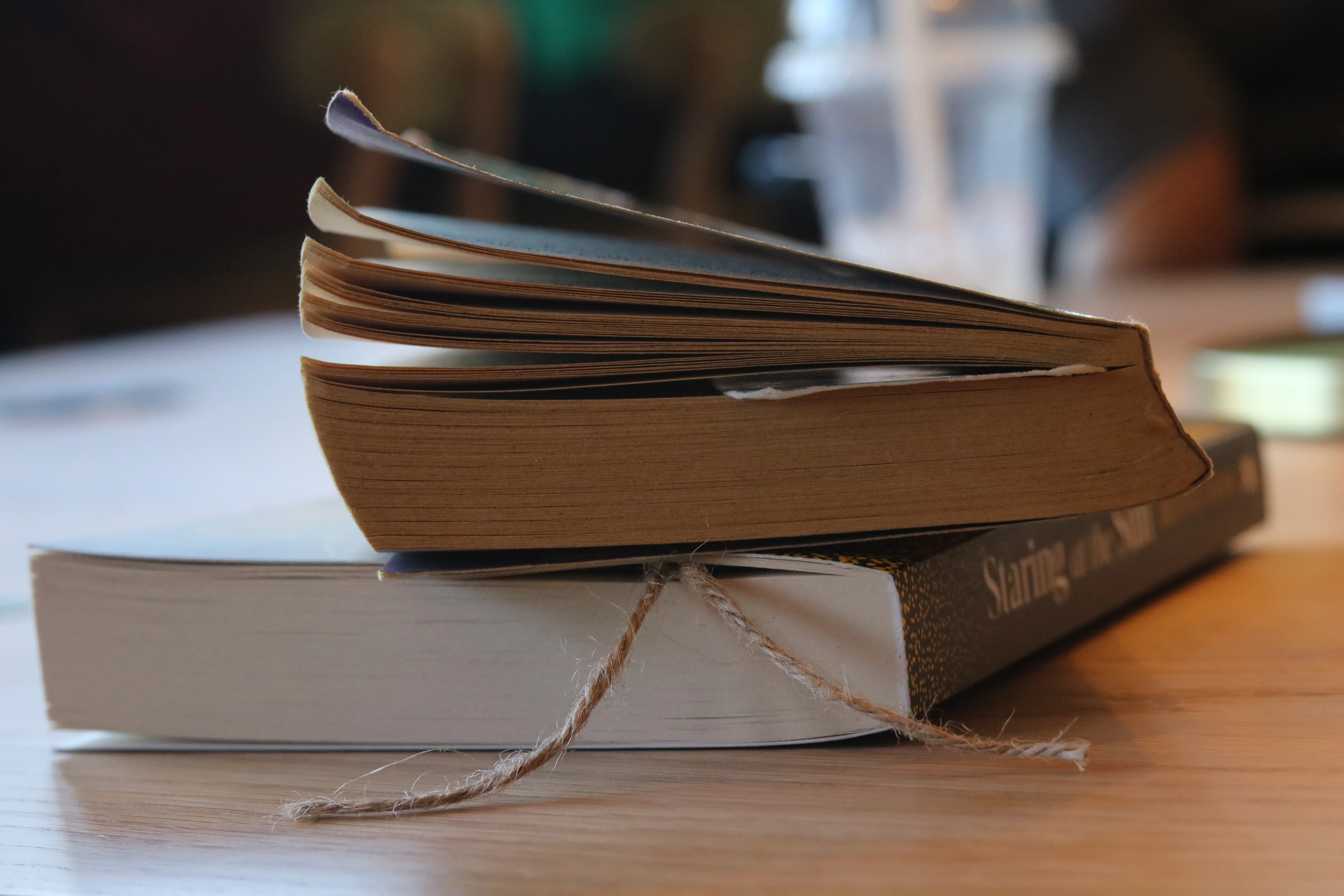 Two printed books stacked on a wooden table, showing their covers and page edges
