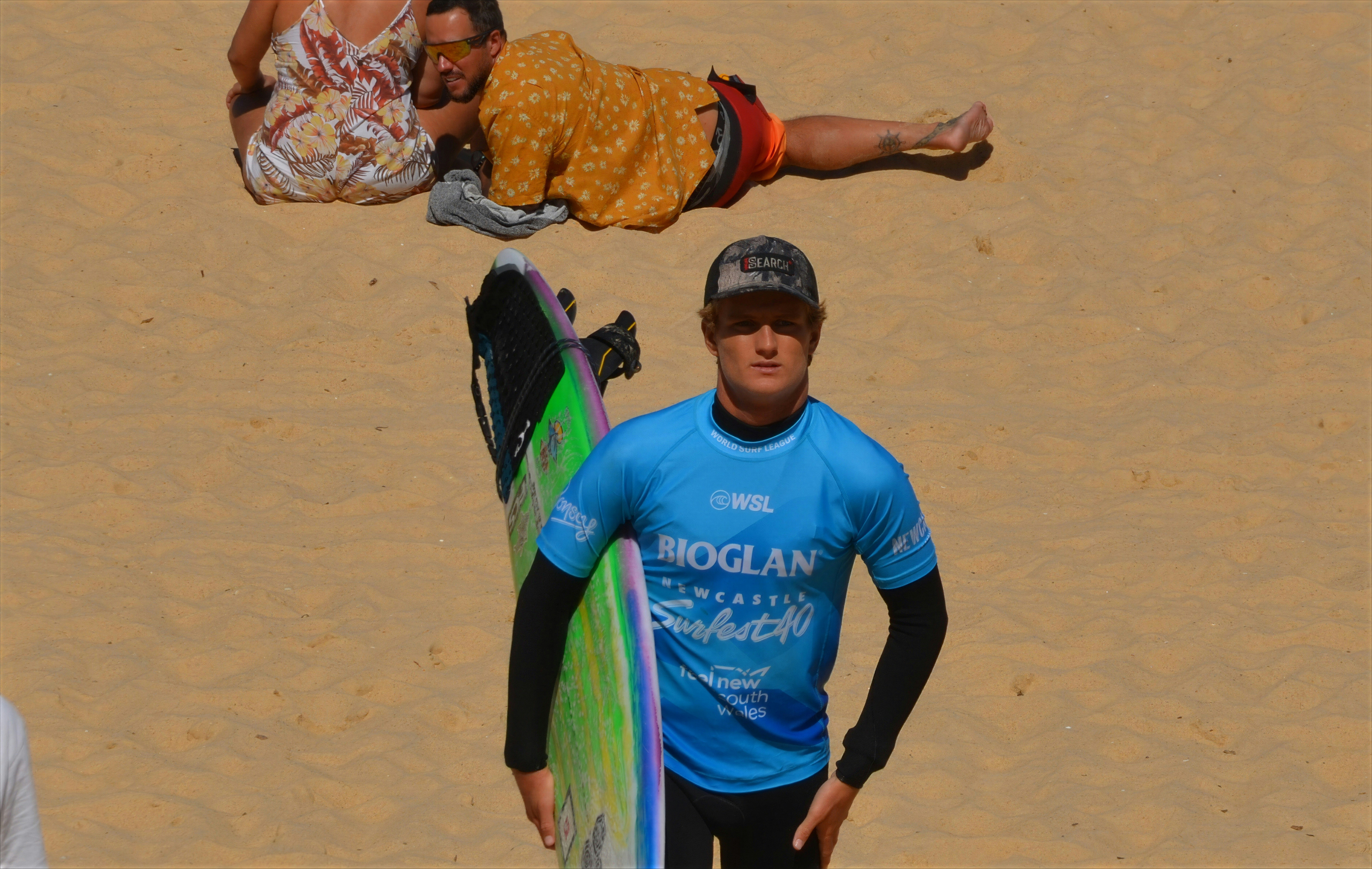 Surfer with board on sandy beach
