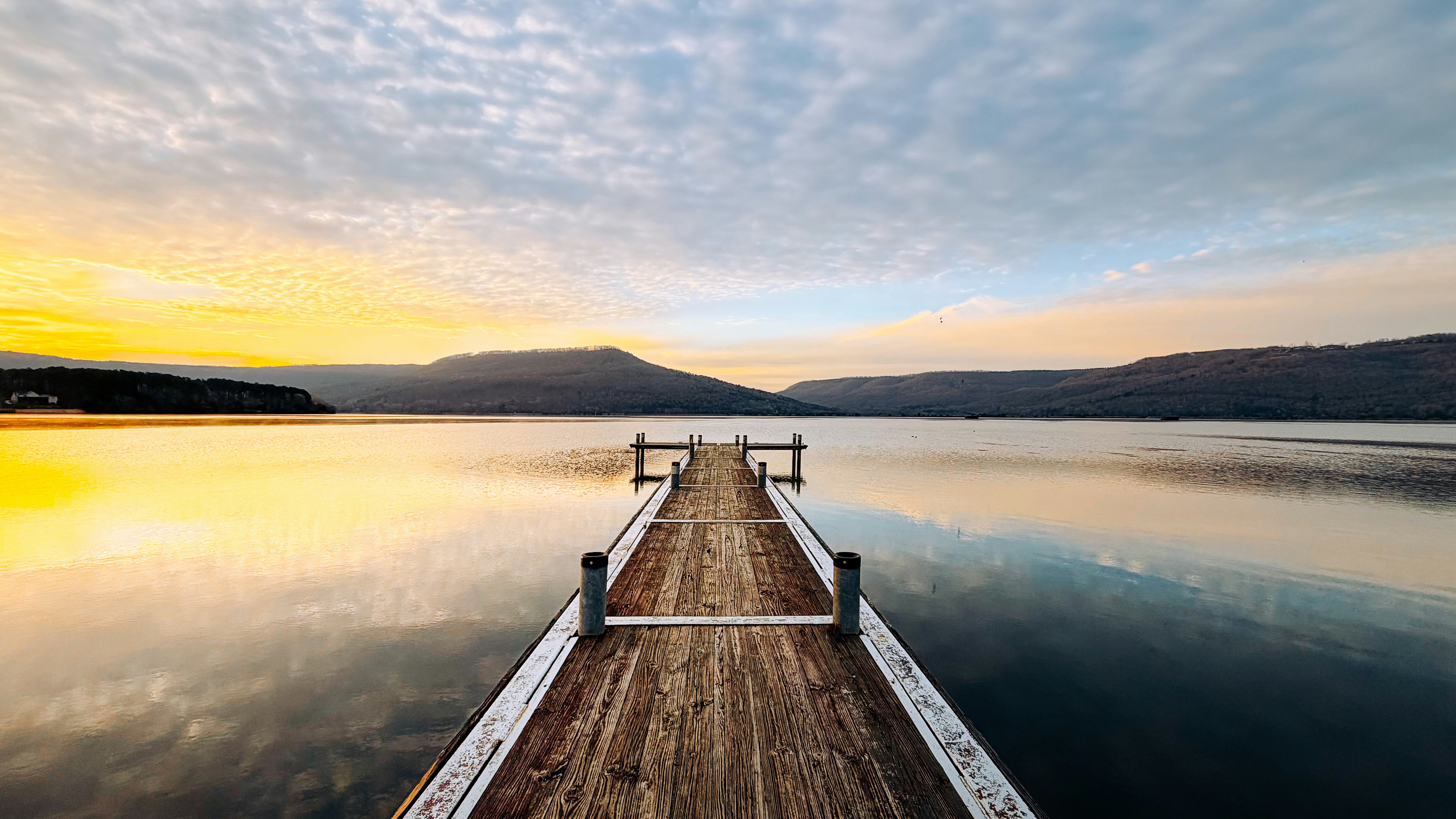 Wooden pier stretching across a calm lake at sunset.