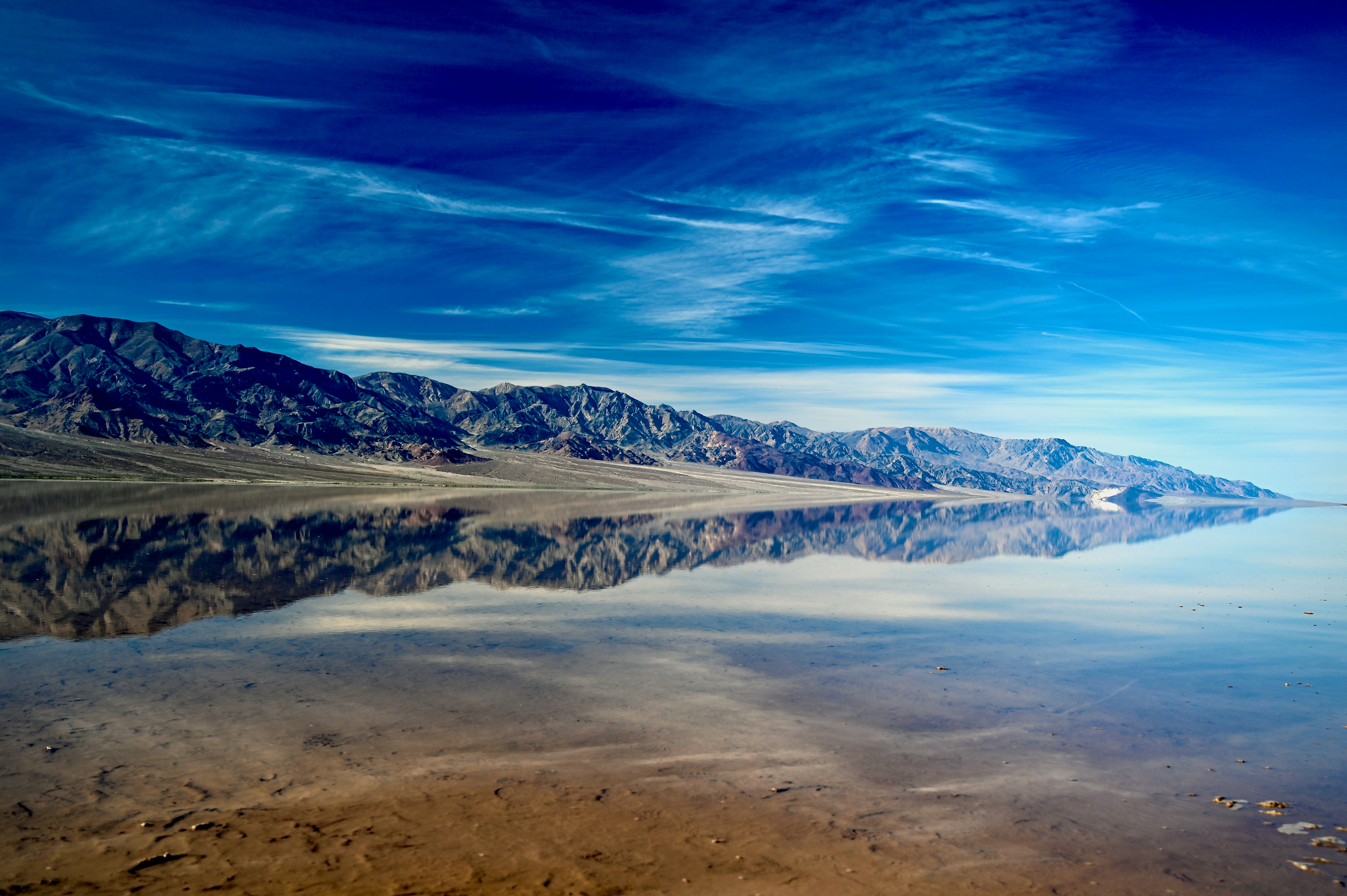 Mountains reflected in a calm, shallow body of water