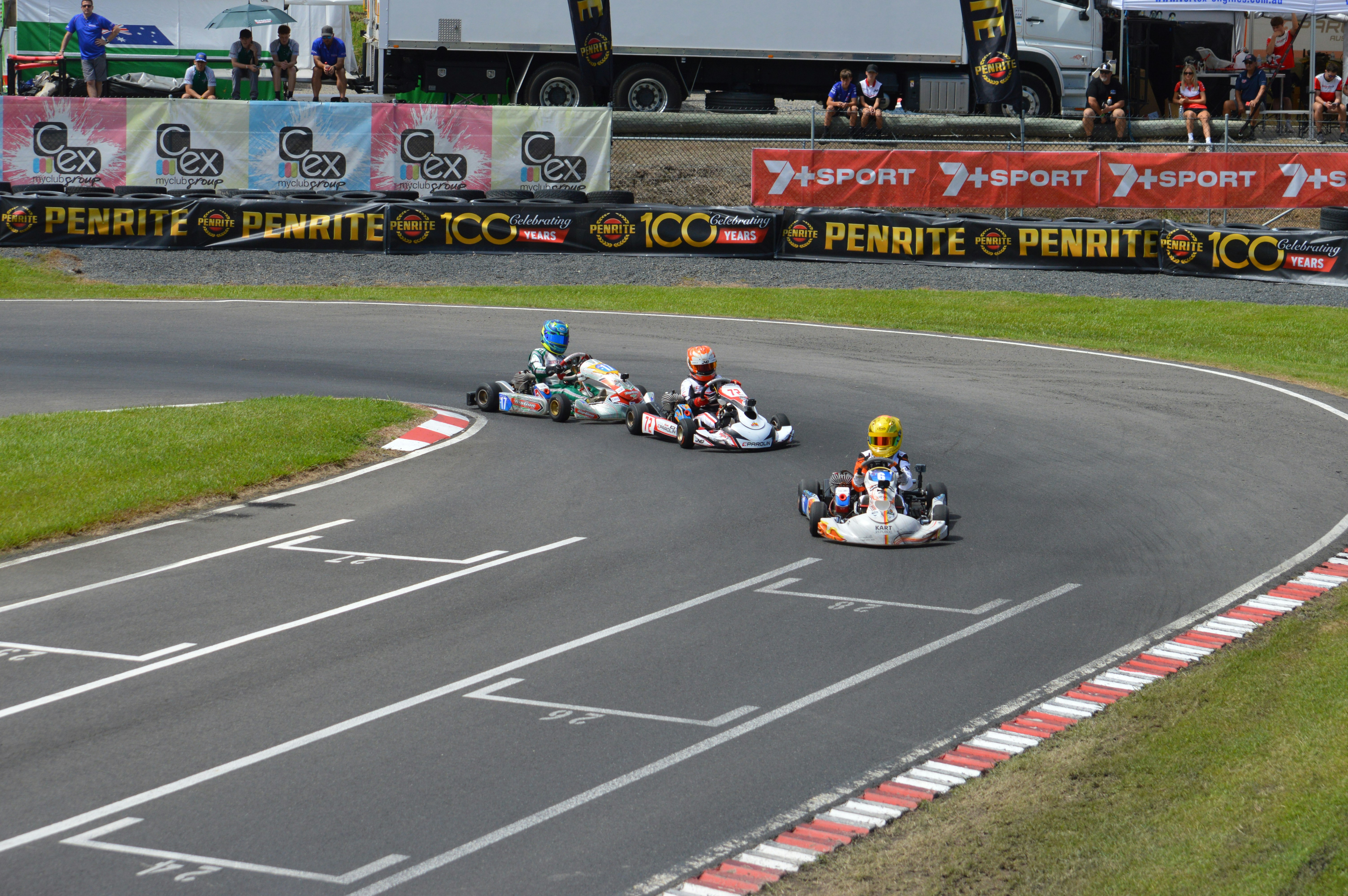 Tiga go-kart berlomba di tikungan di trek.