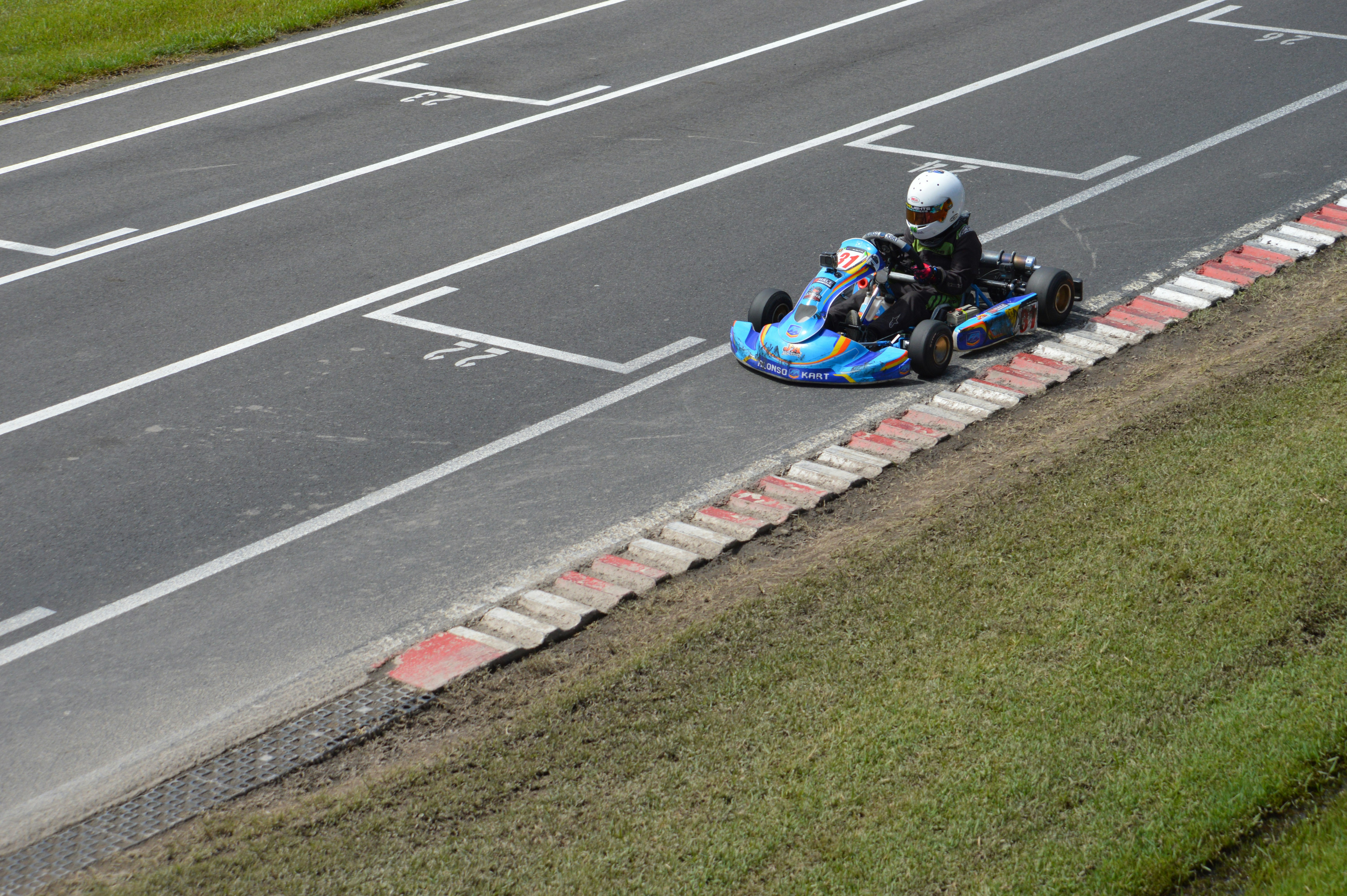 Sebuah go-kart balapan di trek dengan garis putih.
