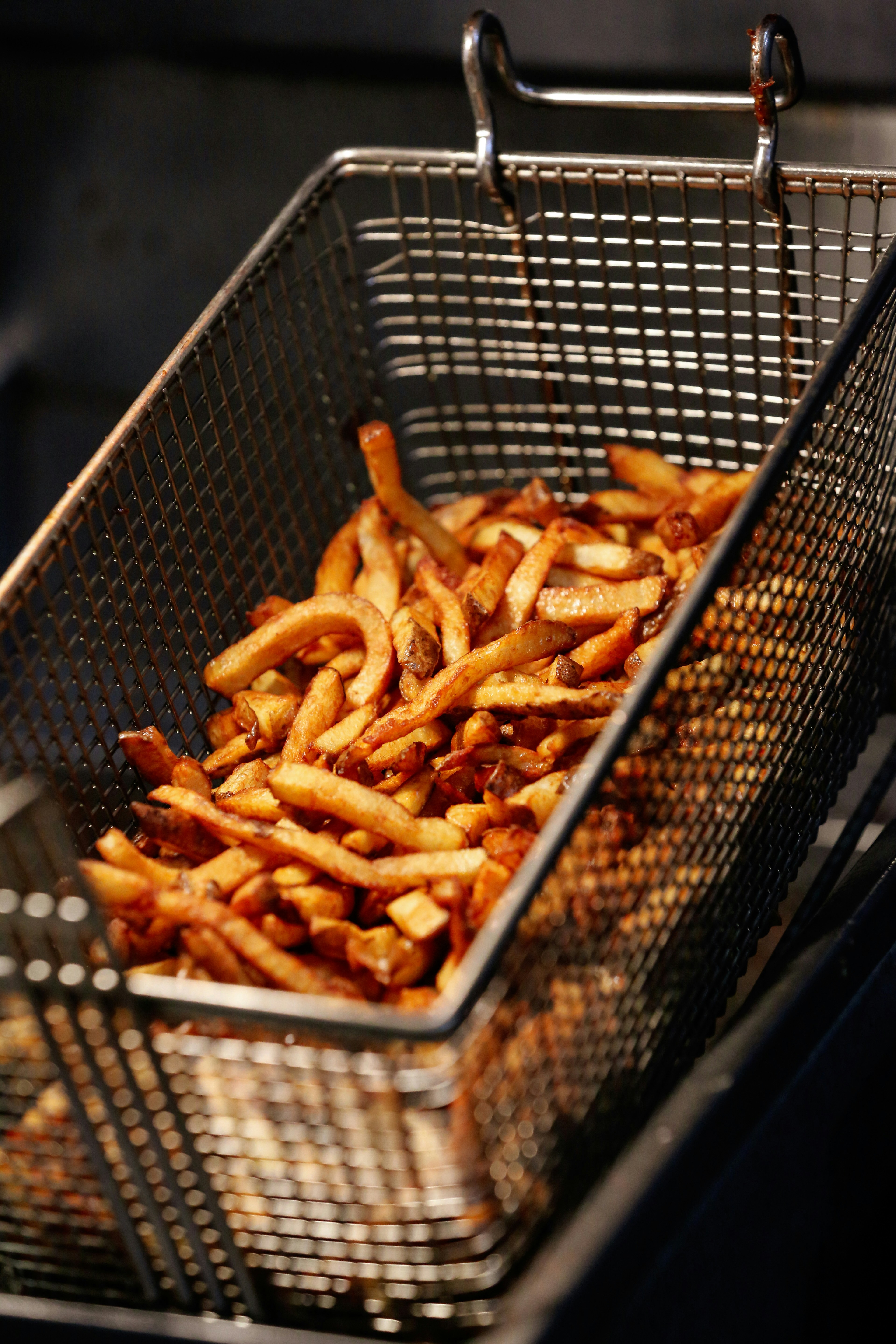 Golden french fries cooking in a metal basket