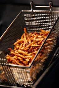 Golden french fries cooking in a metal basket
