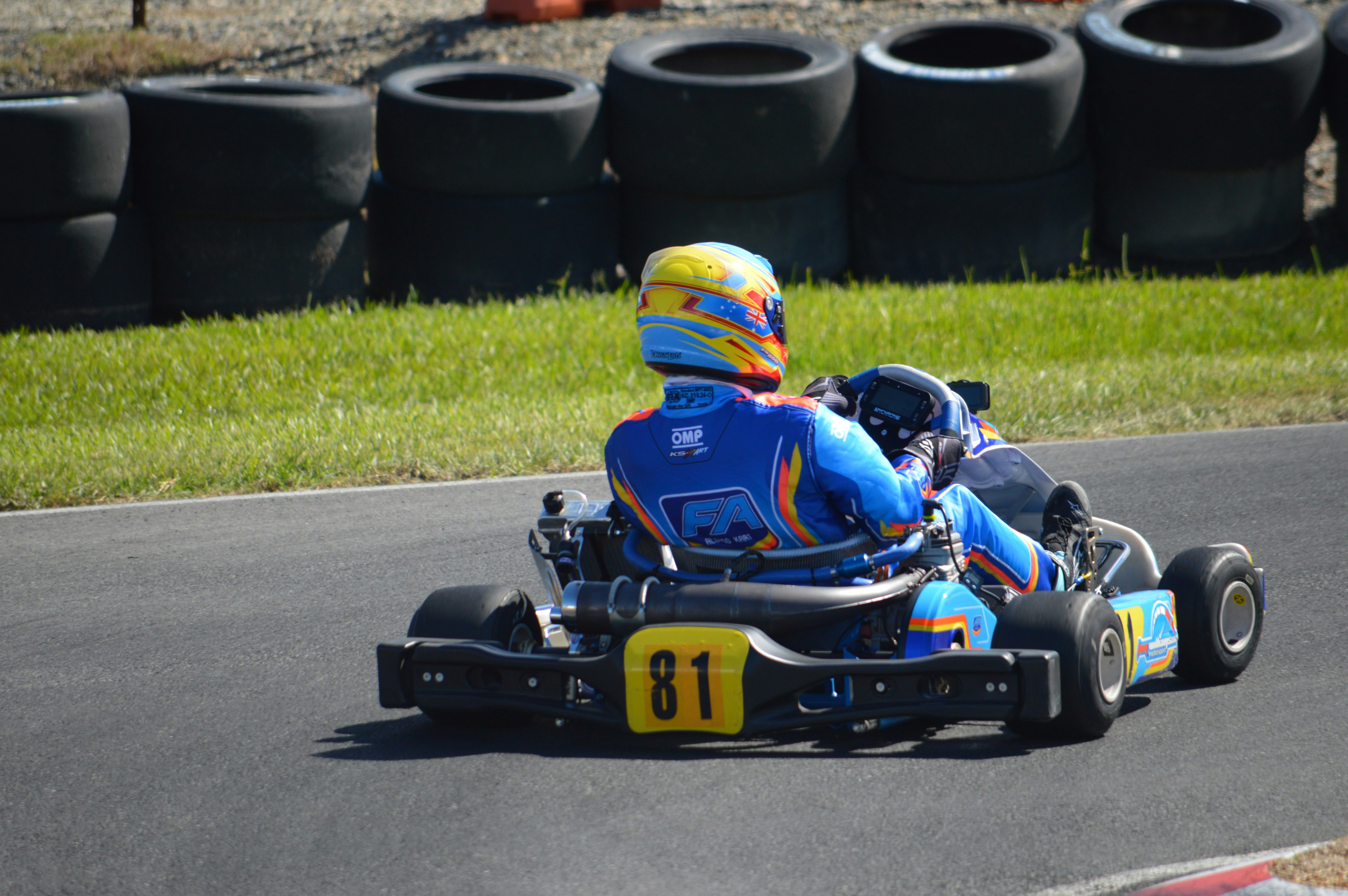 Seorang pembalap go-kart dengan setelan biru di trek.