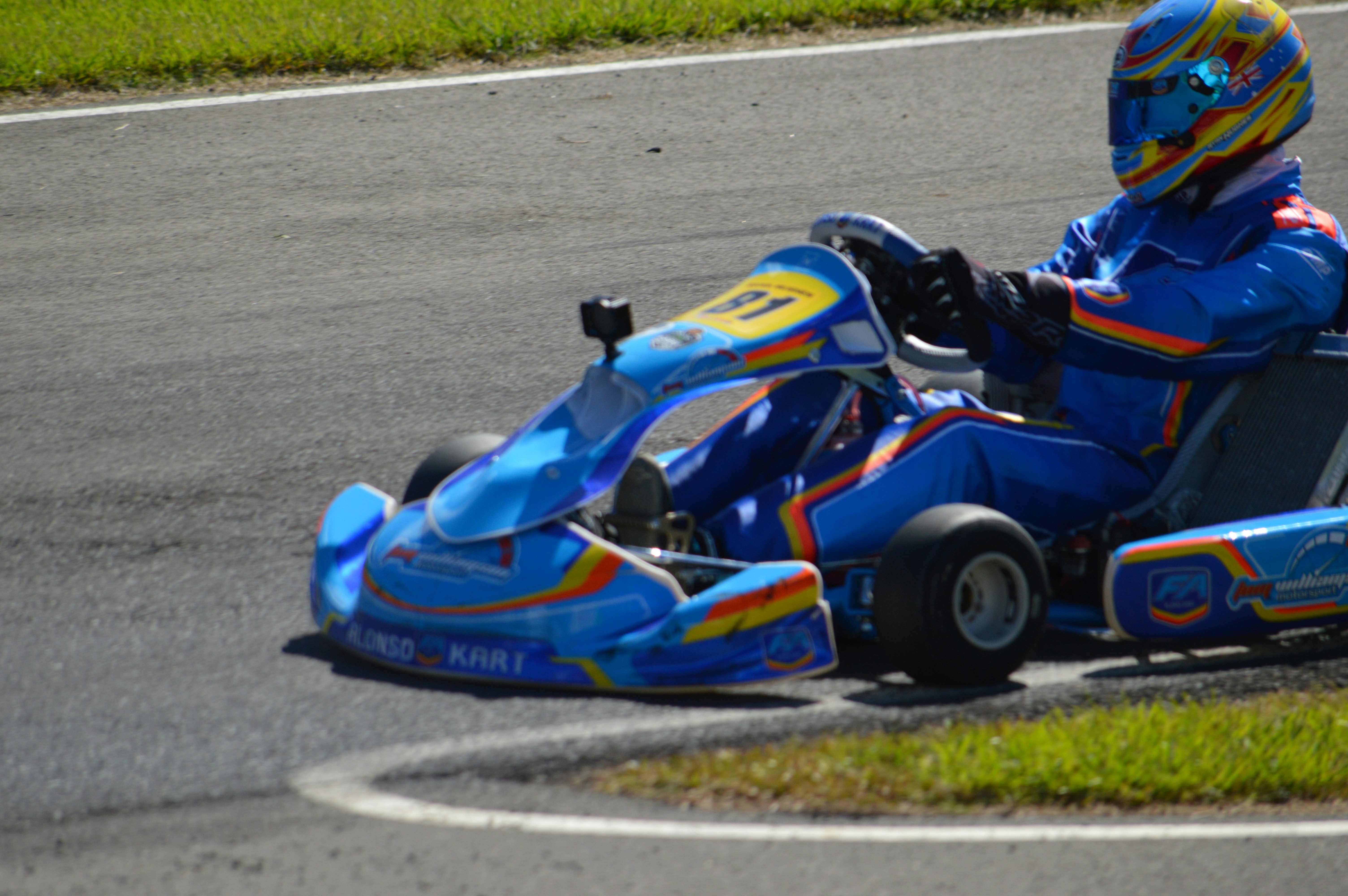 Go-kart biru dengan pengemudi di trek balap