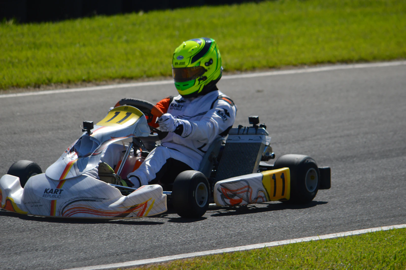 A driver in a lime helmet cornering a white race kart