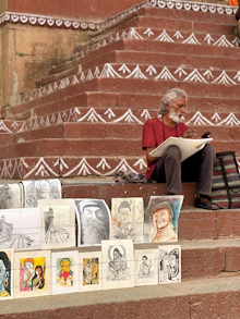 Artist sketching on steps with artwork displayed