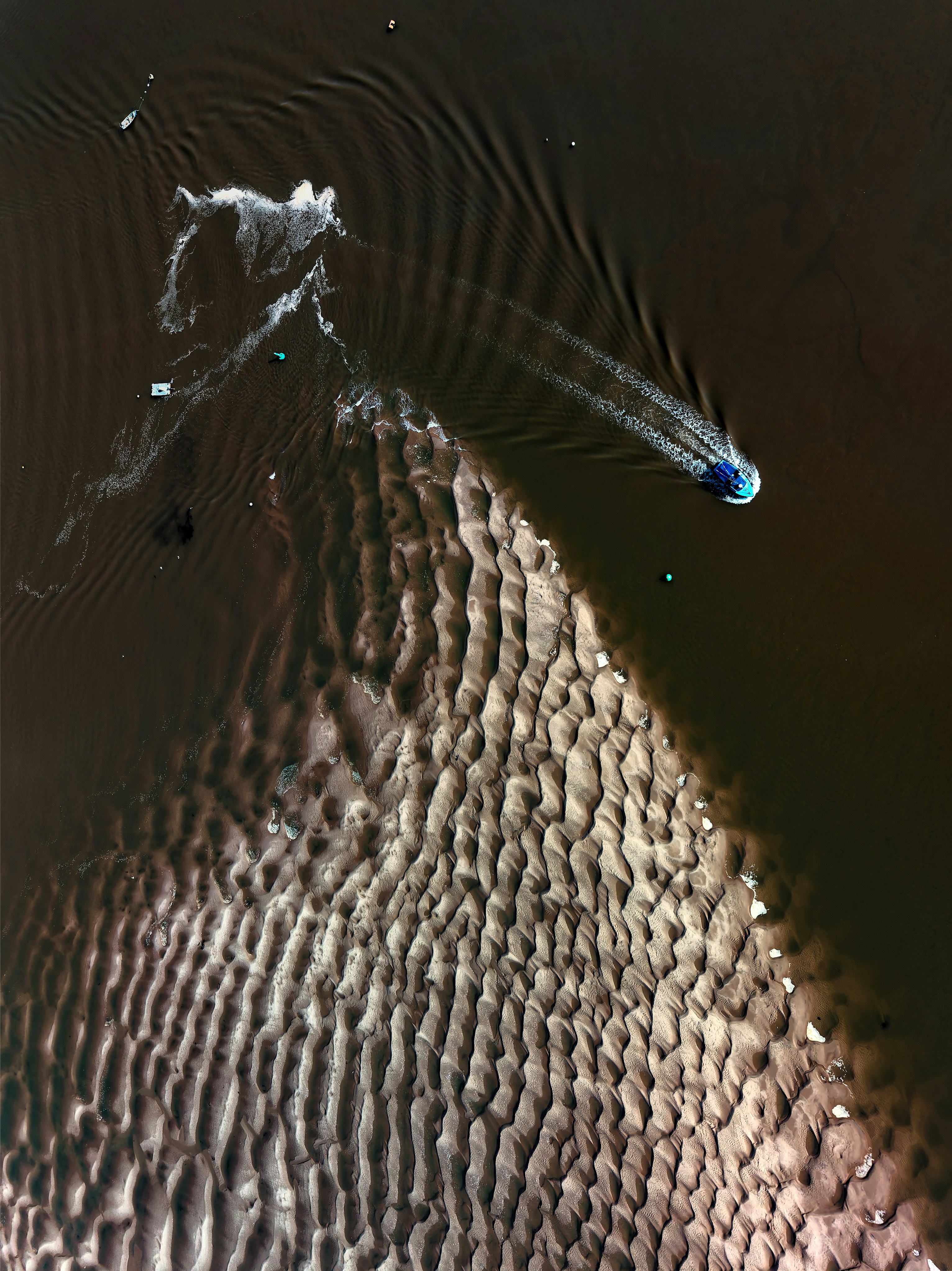 Bateau naviguant sur des eaux sombres près d’un banc de sable ondulé