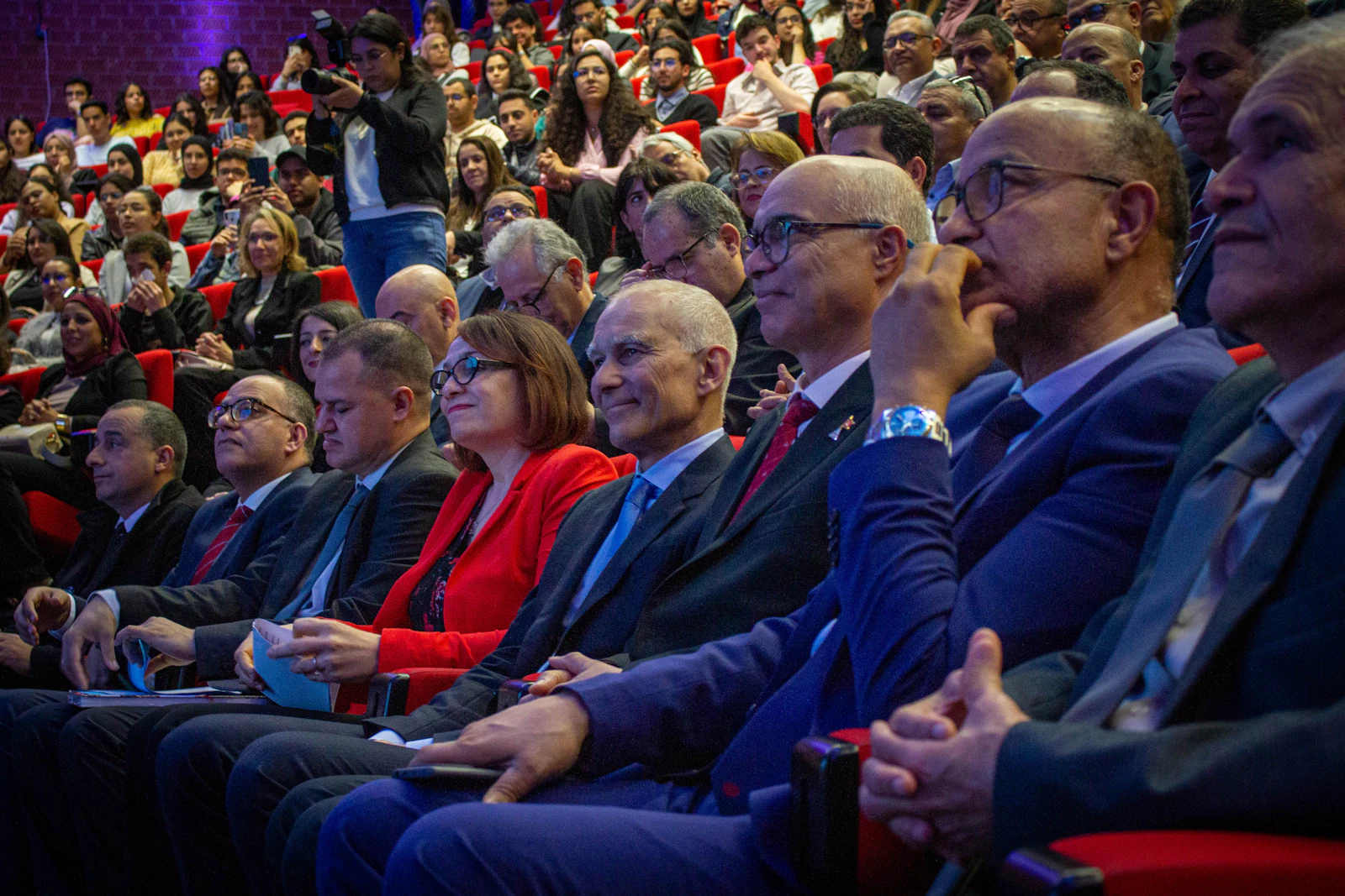 An audience seated in a conference hall watching a presentation