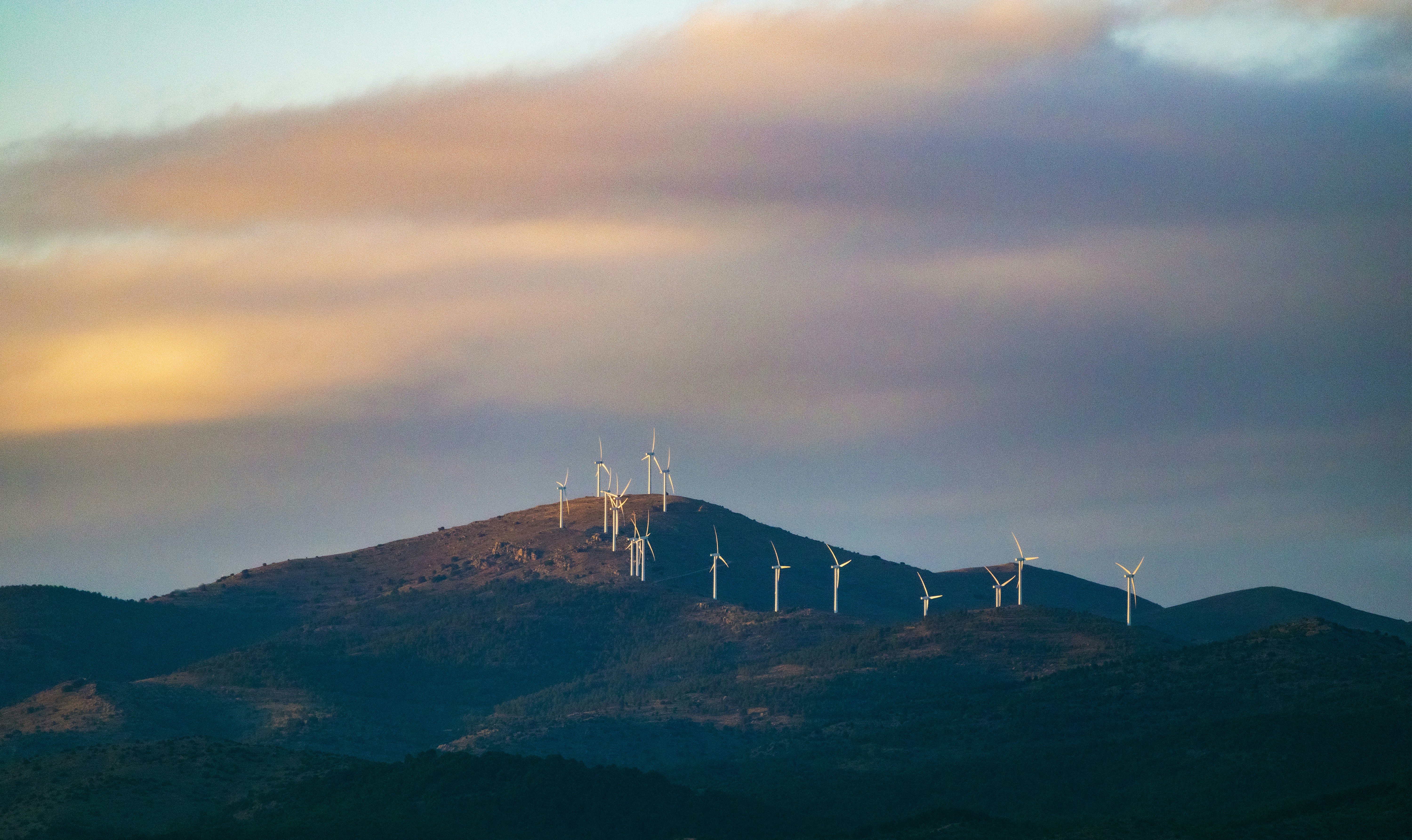 Wind turbines on a distant, cloudy mountain ridge.