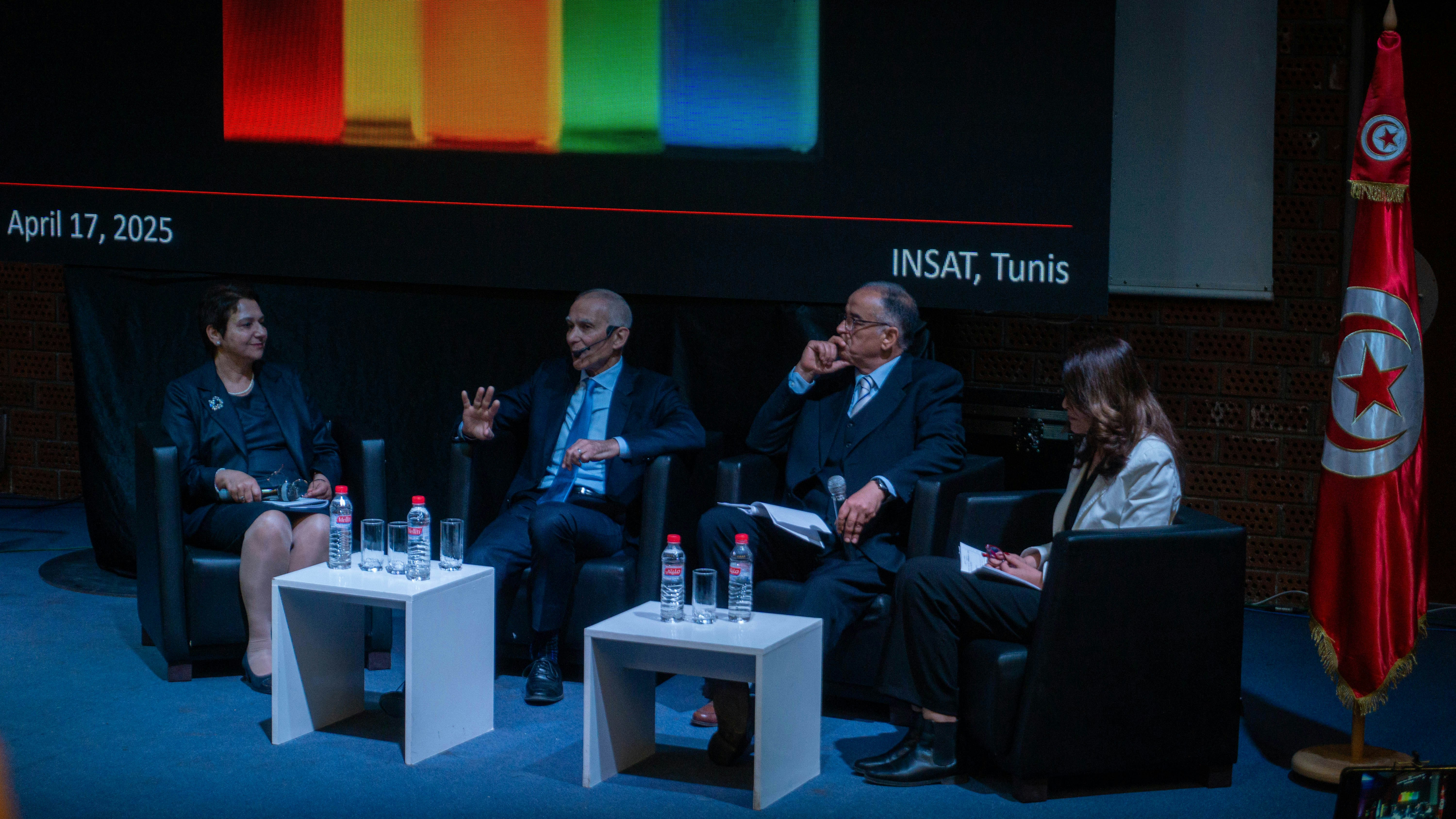Four people sit on a stage at a panel discussion.