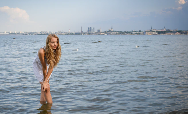 Young woman in white dress standing in calm water
