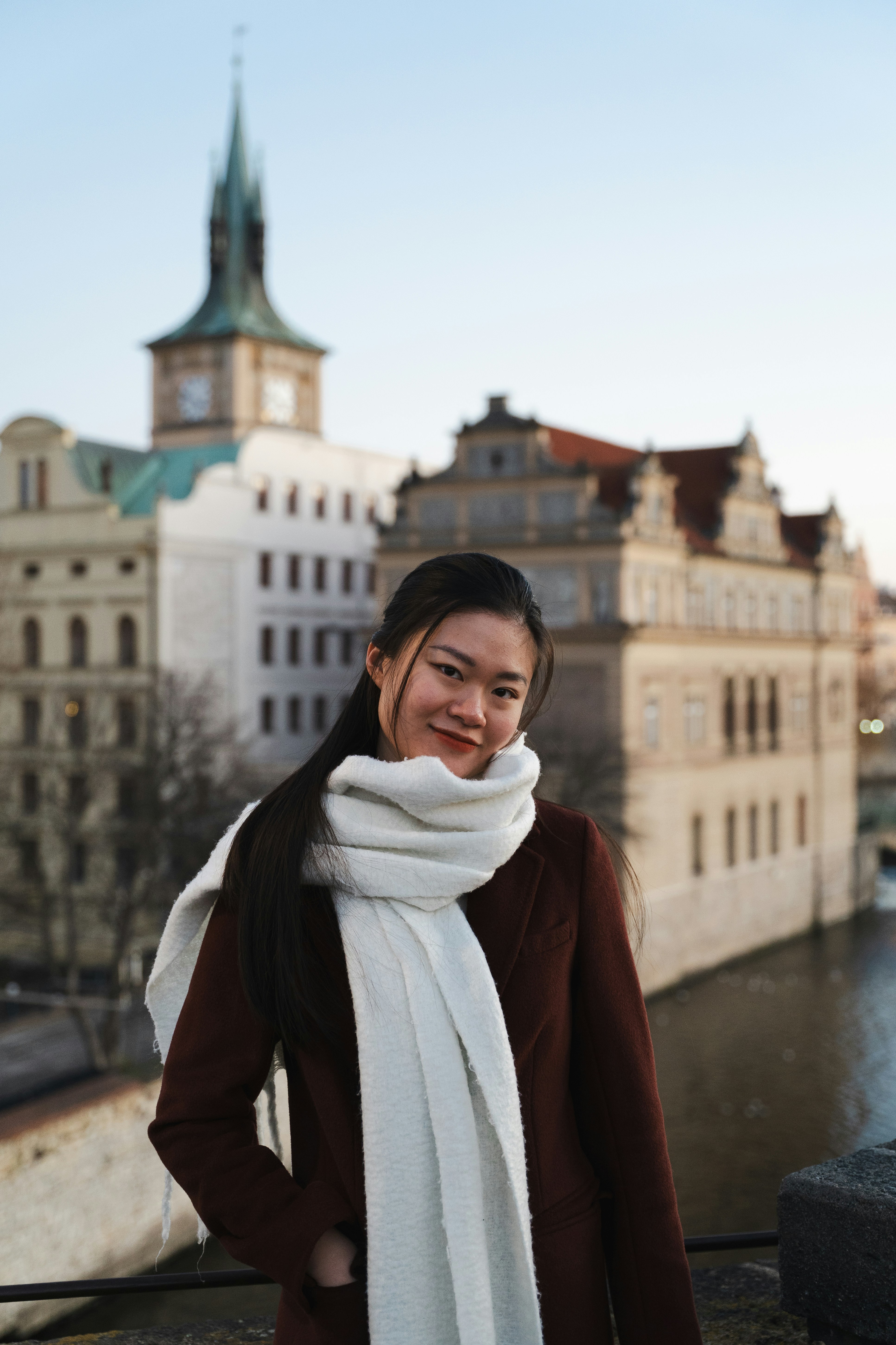Young woman in scarf with historic buildings behind her.