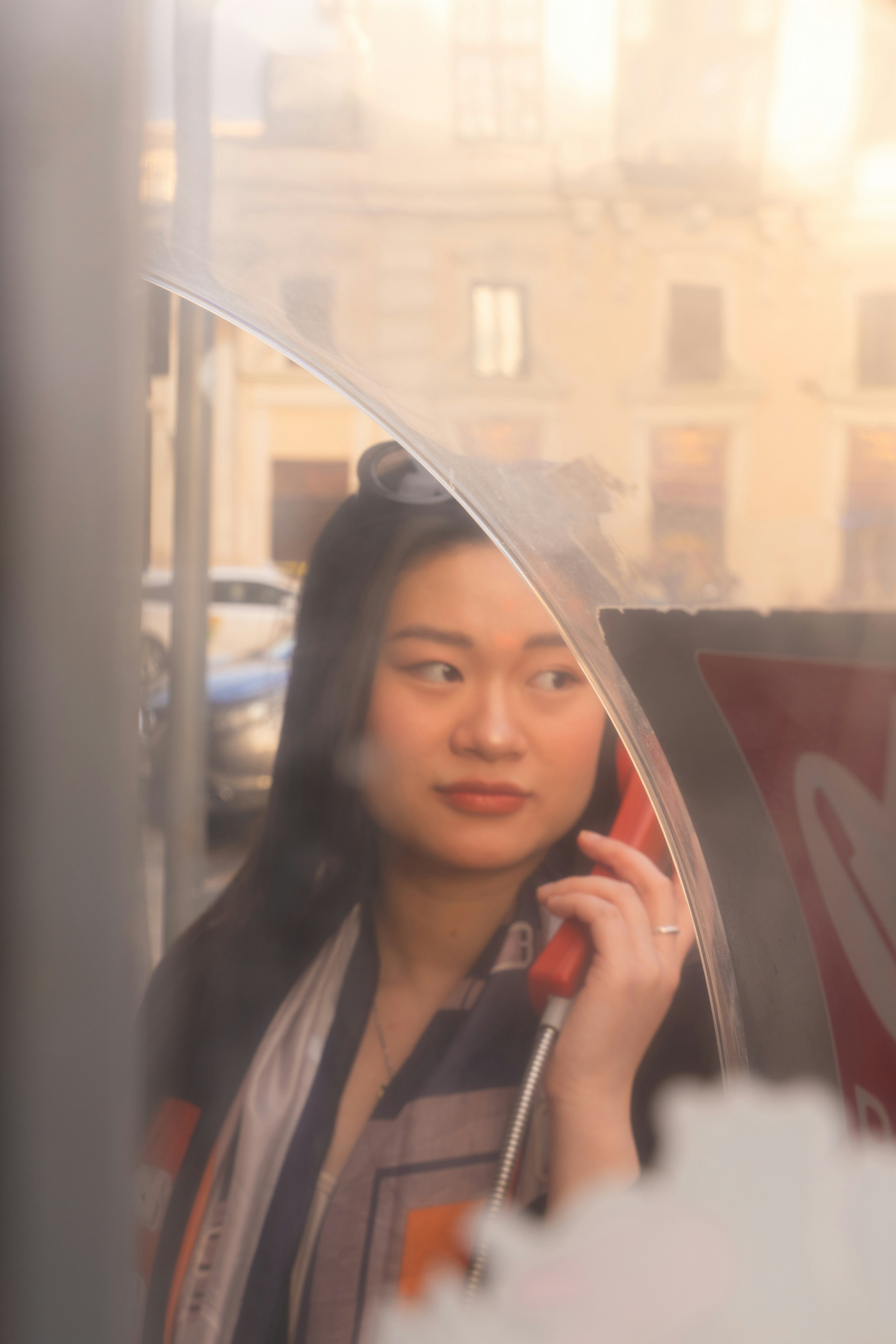 A woman using a red payphone in a booth