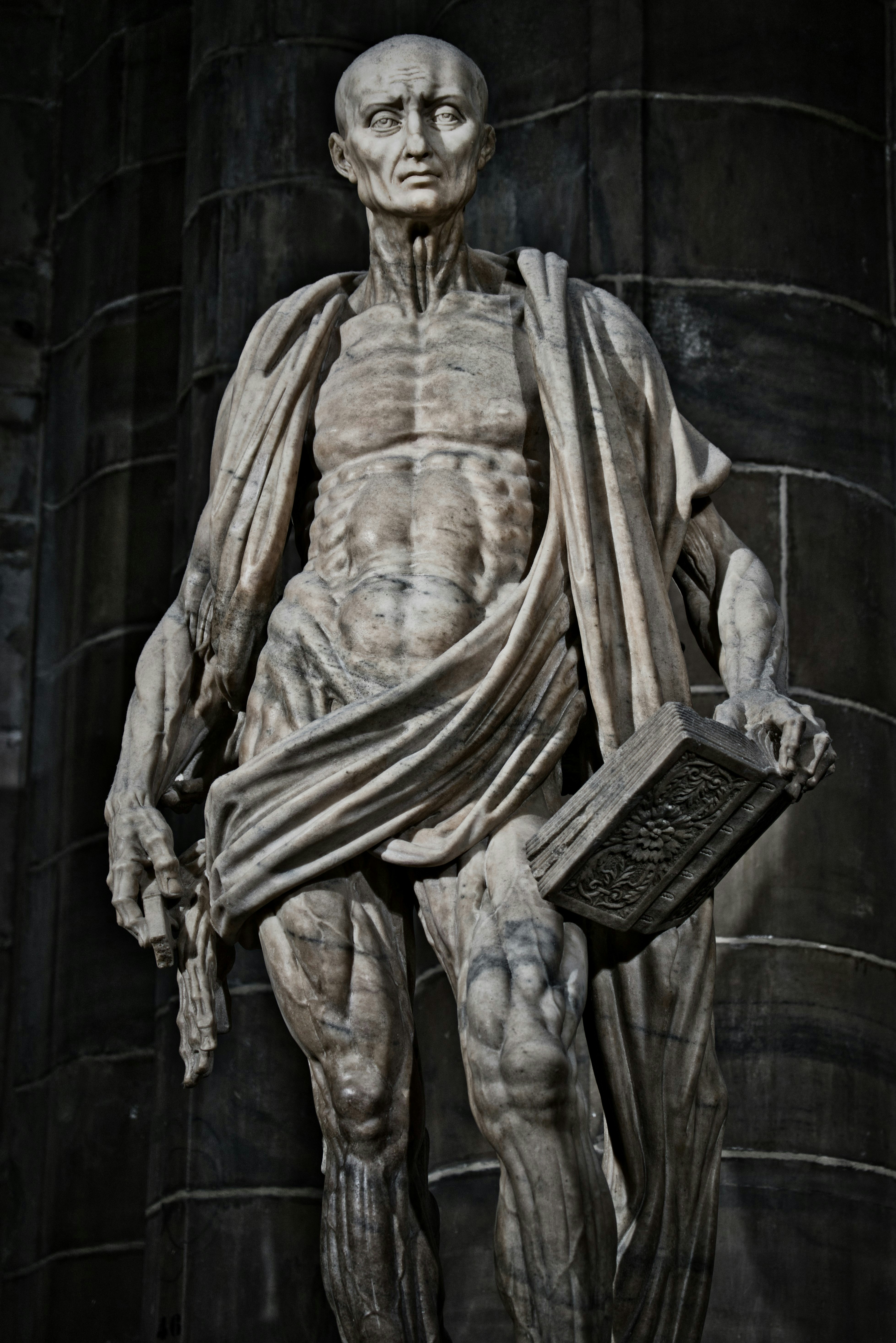 Marble statue of a gaunt man holding a book