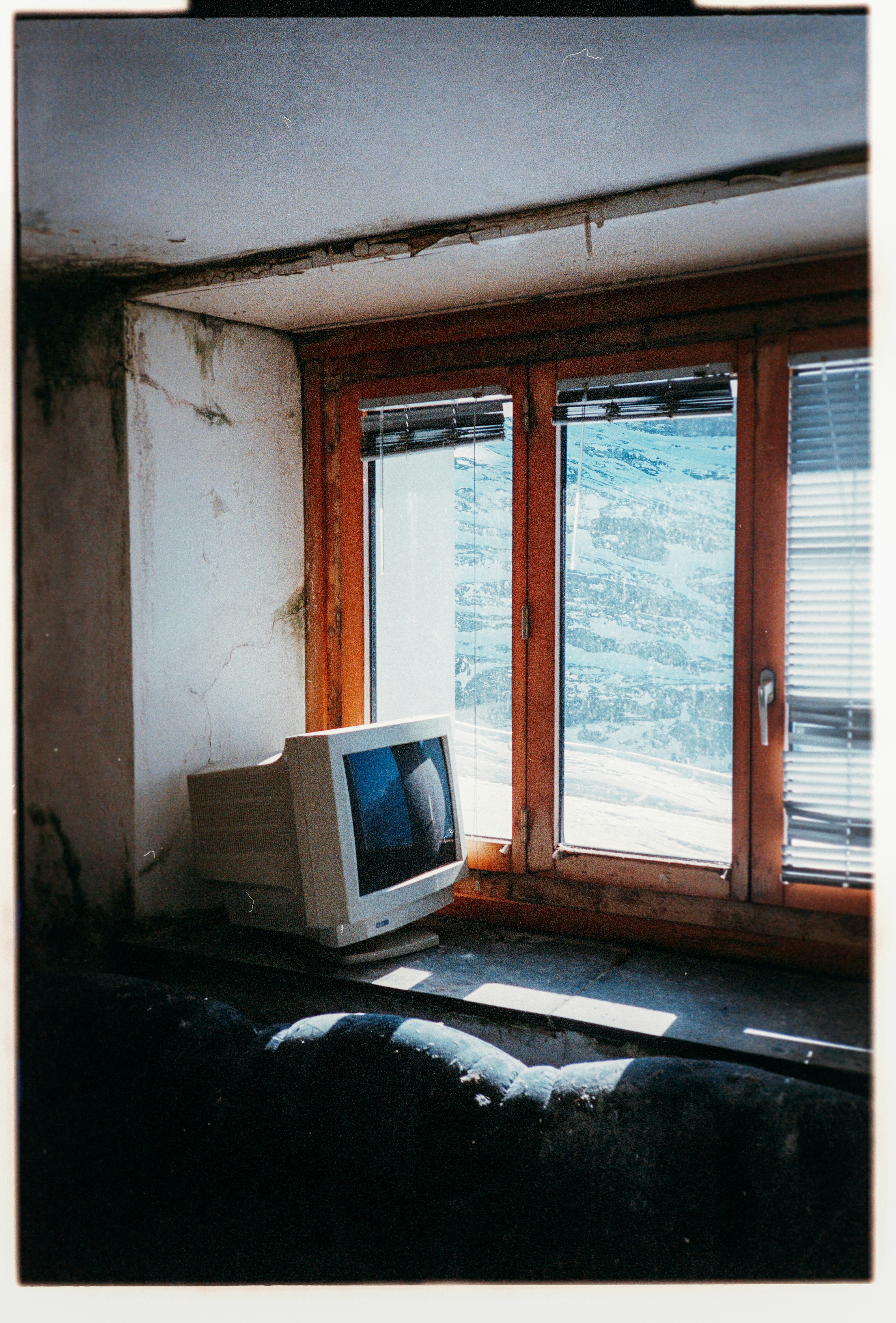 Alter Computermonitor auf einer Fensterbank neben einem Fenster.