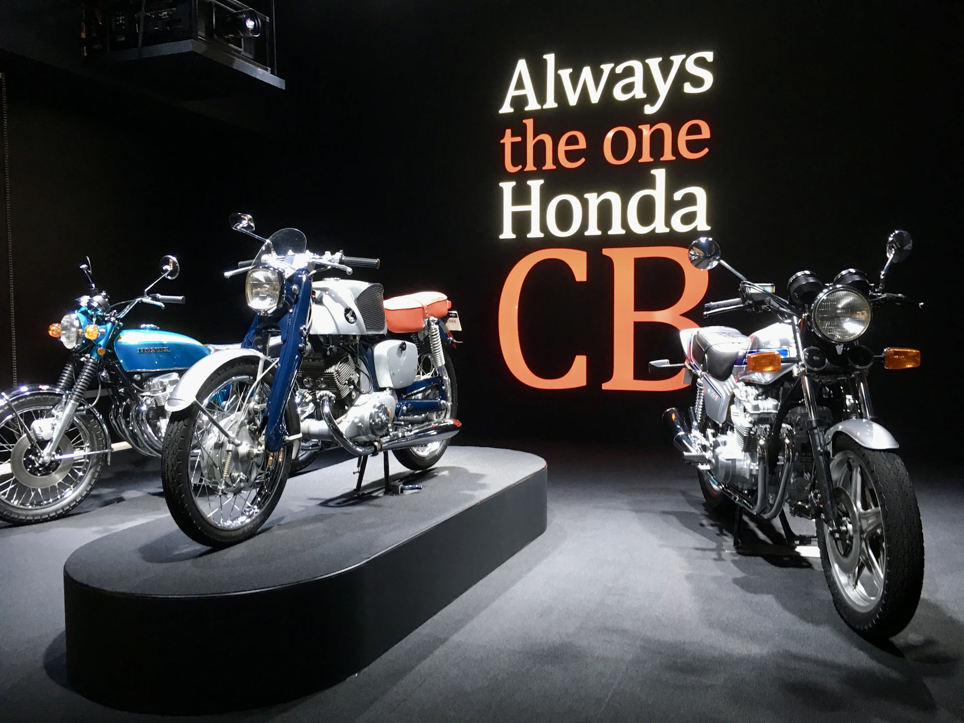 Three vintage honda motorcycles displayed on pedestals.