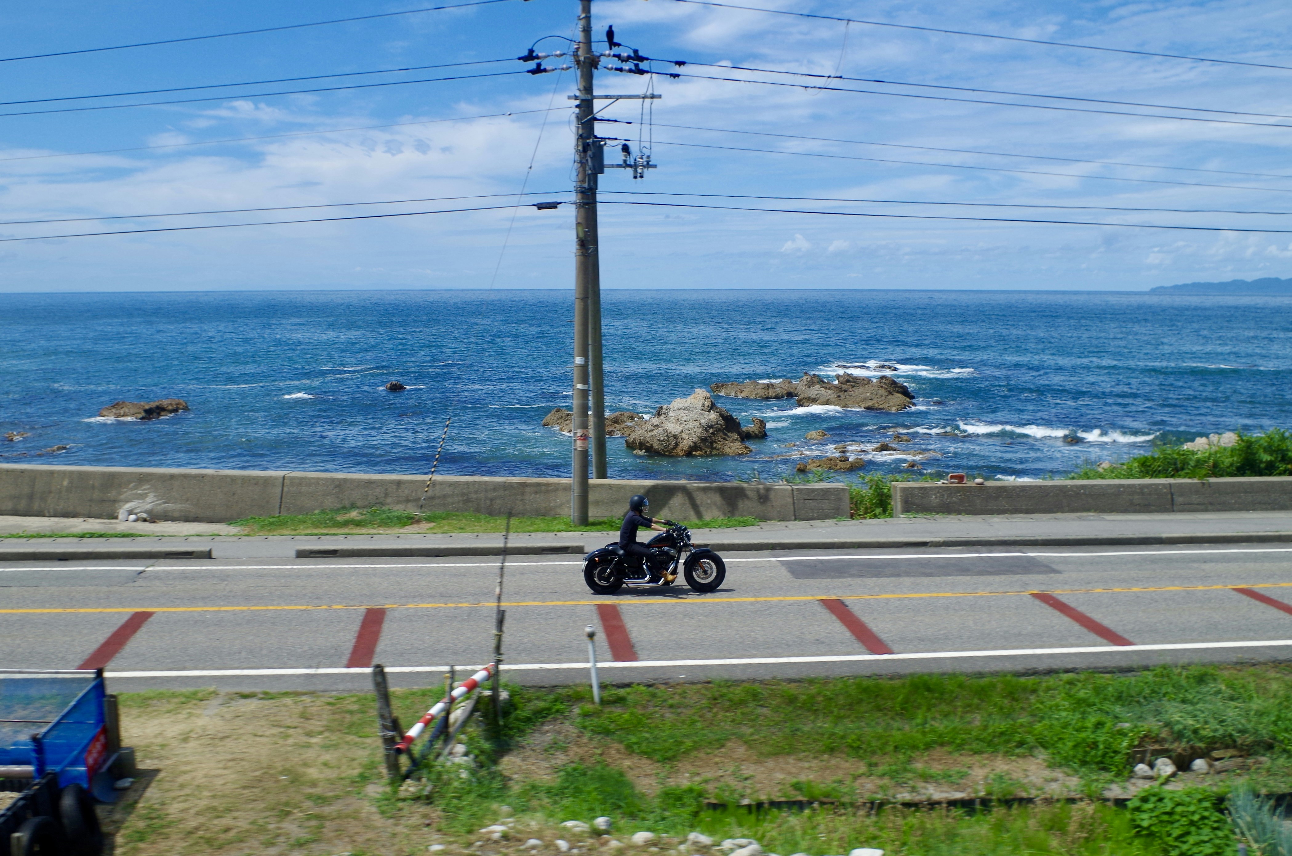 A person rides a small vehicle by the ocean.