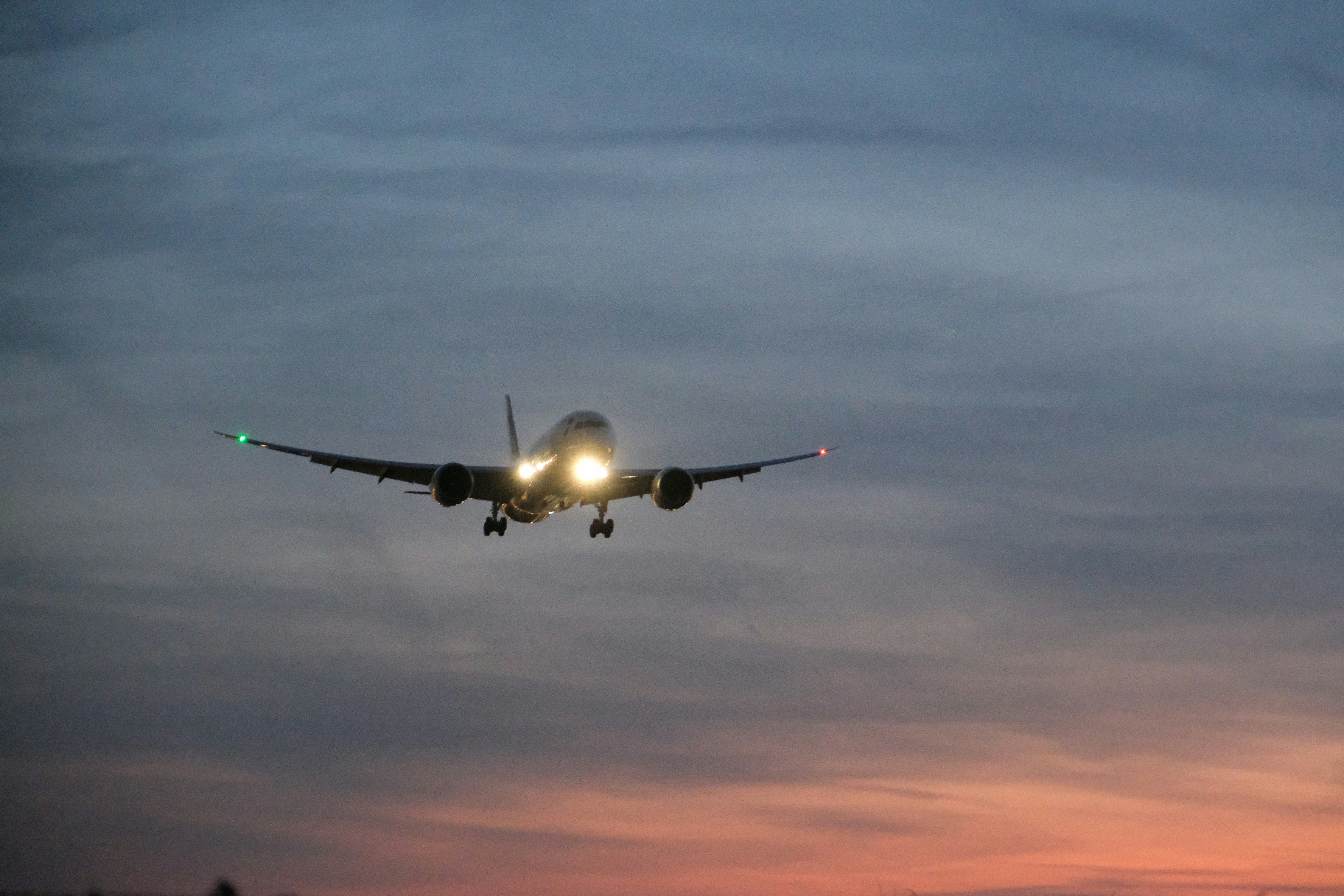 Airplane landing at dusk with lights on