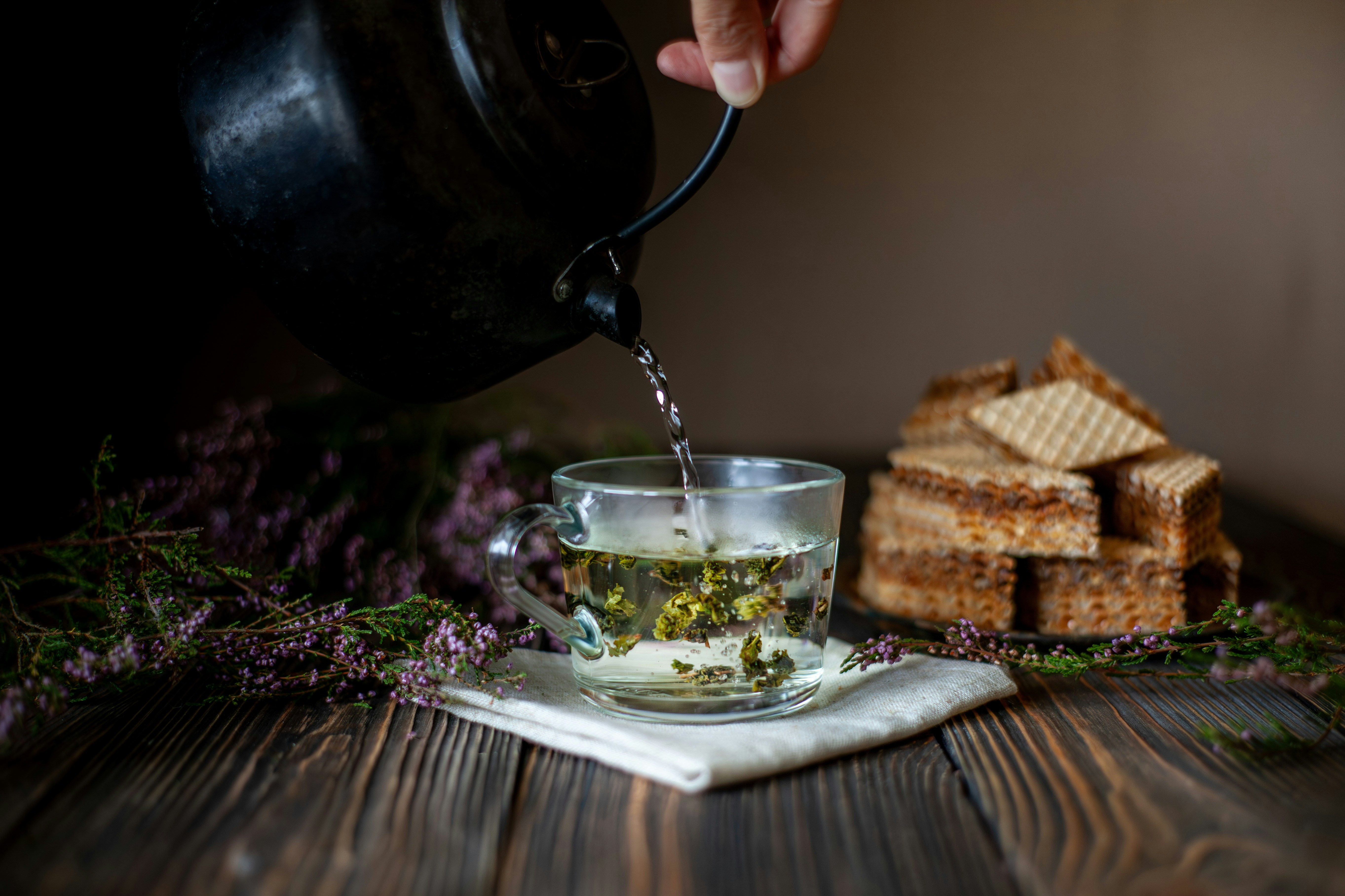 Hot water being poured into a tea cup with wafers.