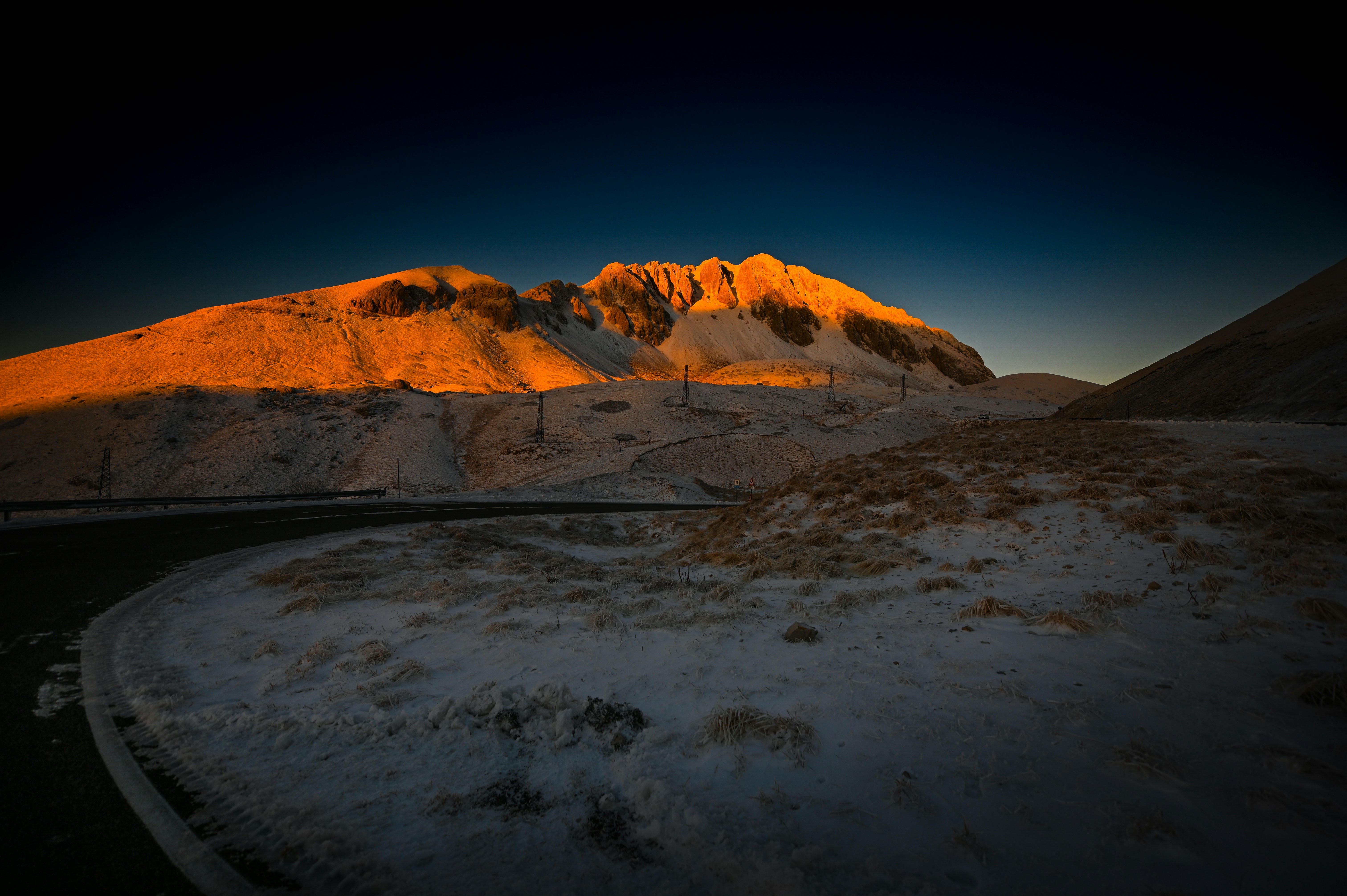 Snowy mountain illuminated by golden sunrise light at sunrise.