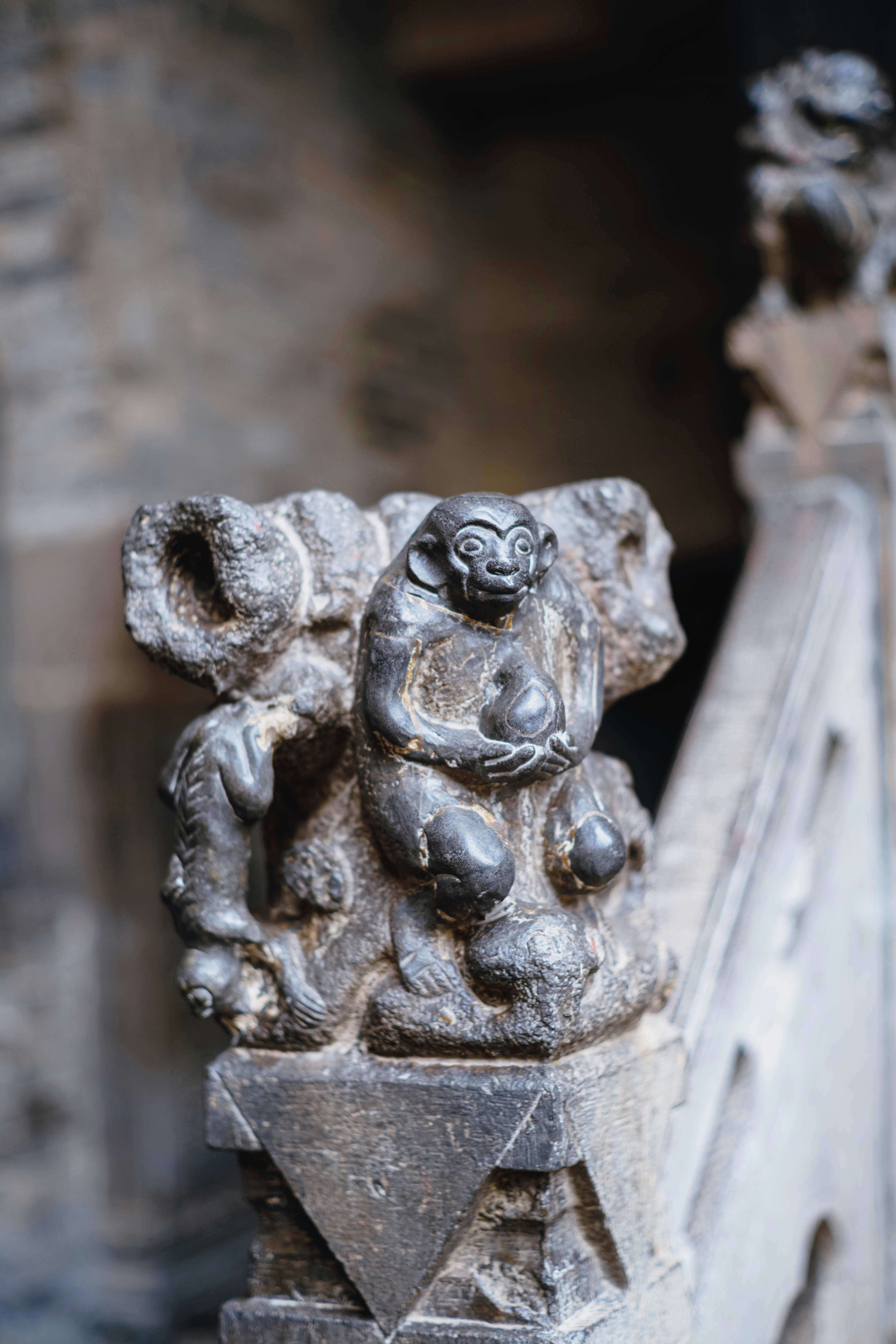 Talla en piedra de monos sobre un pilar decorativo.