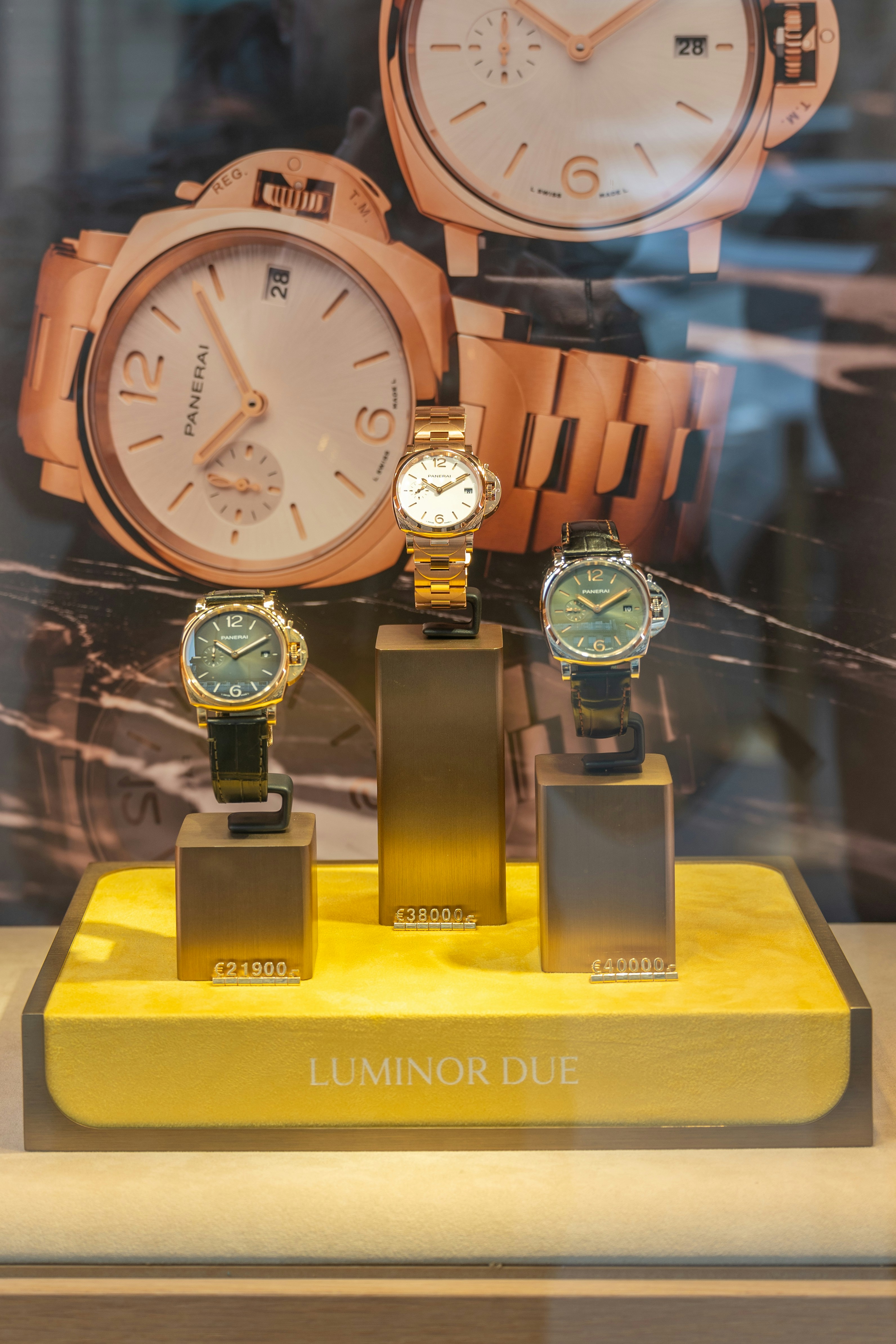 Three luxury watches displayed in a store window.