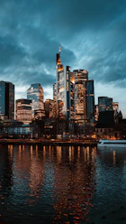 Modern skyscrapers reflected in dark water at dusk