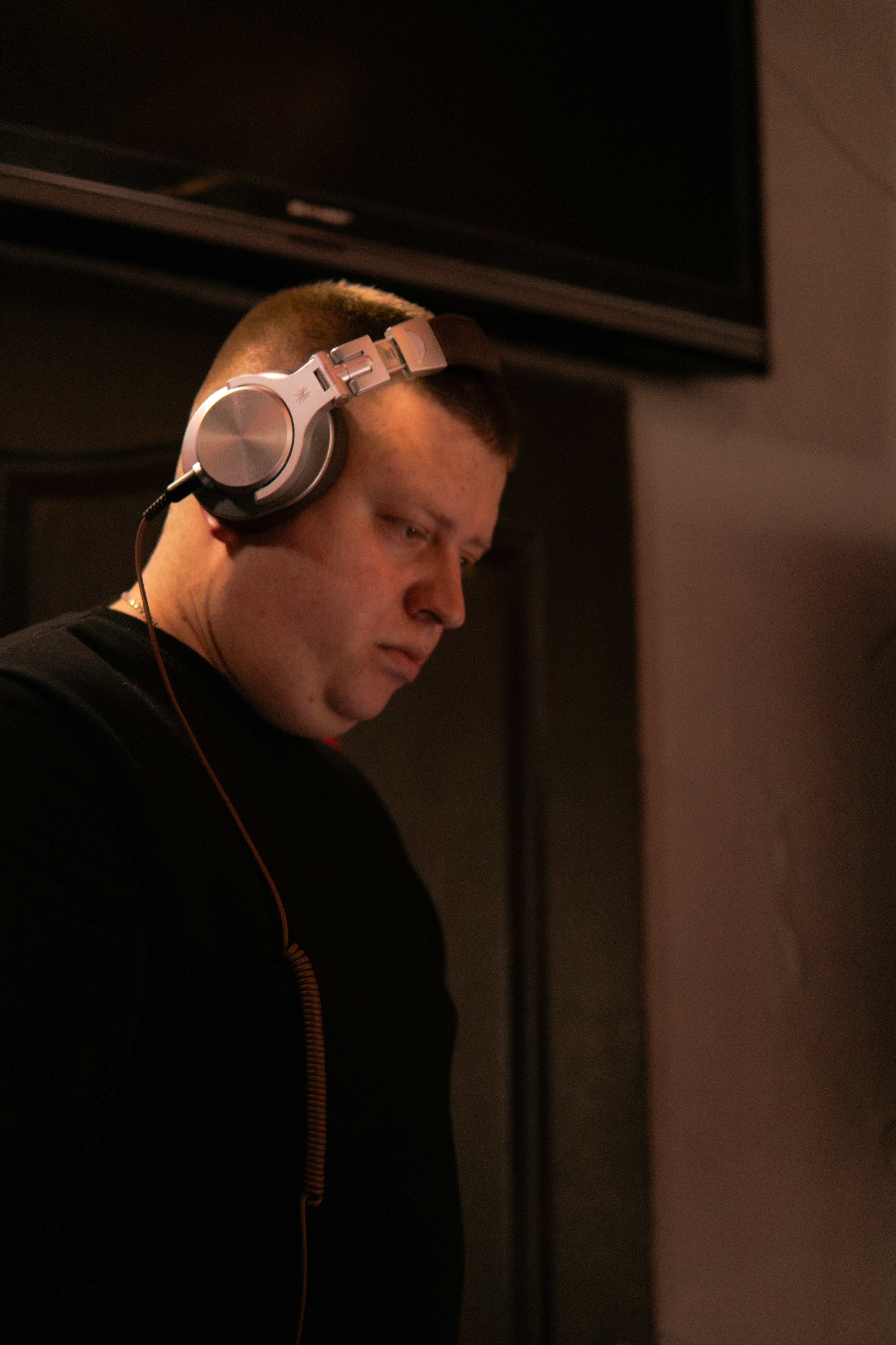 Man wearing headphones, looking down intently downwards.