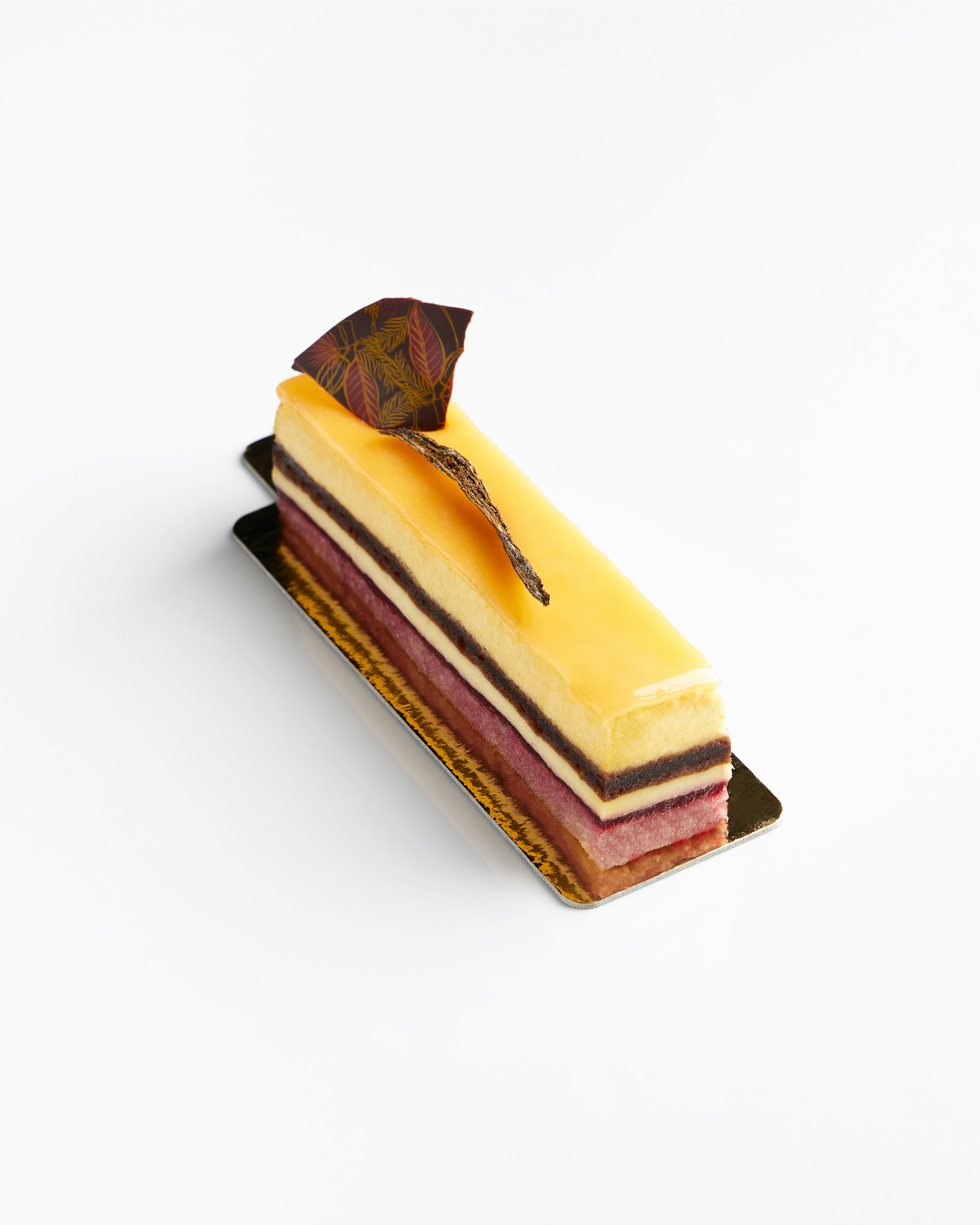 Un postre rectangular con capas y adorno amarillo y adorno de chocolate