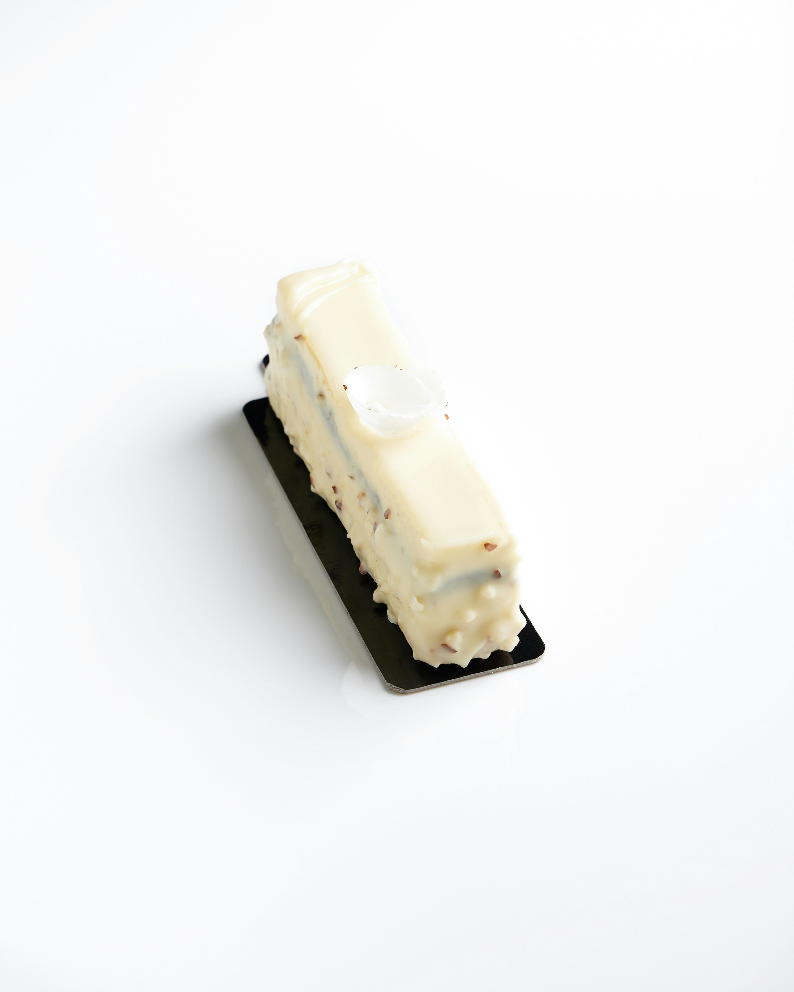 Postre rectangular de chocolate blanco sobre base negra