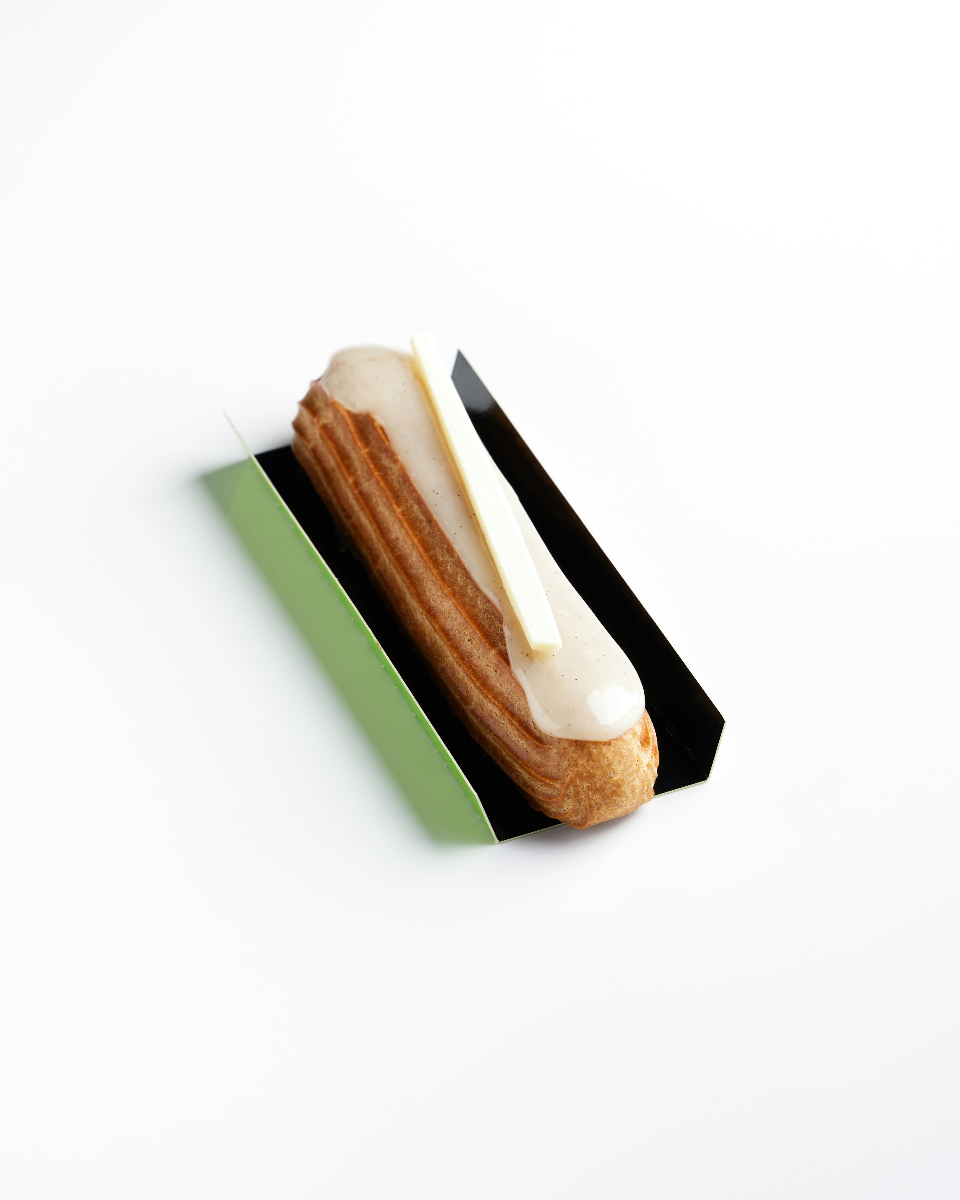Un solo éclair con glaseado blanco y adorno de chocolate.