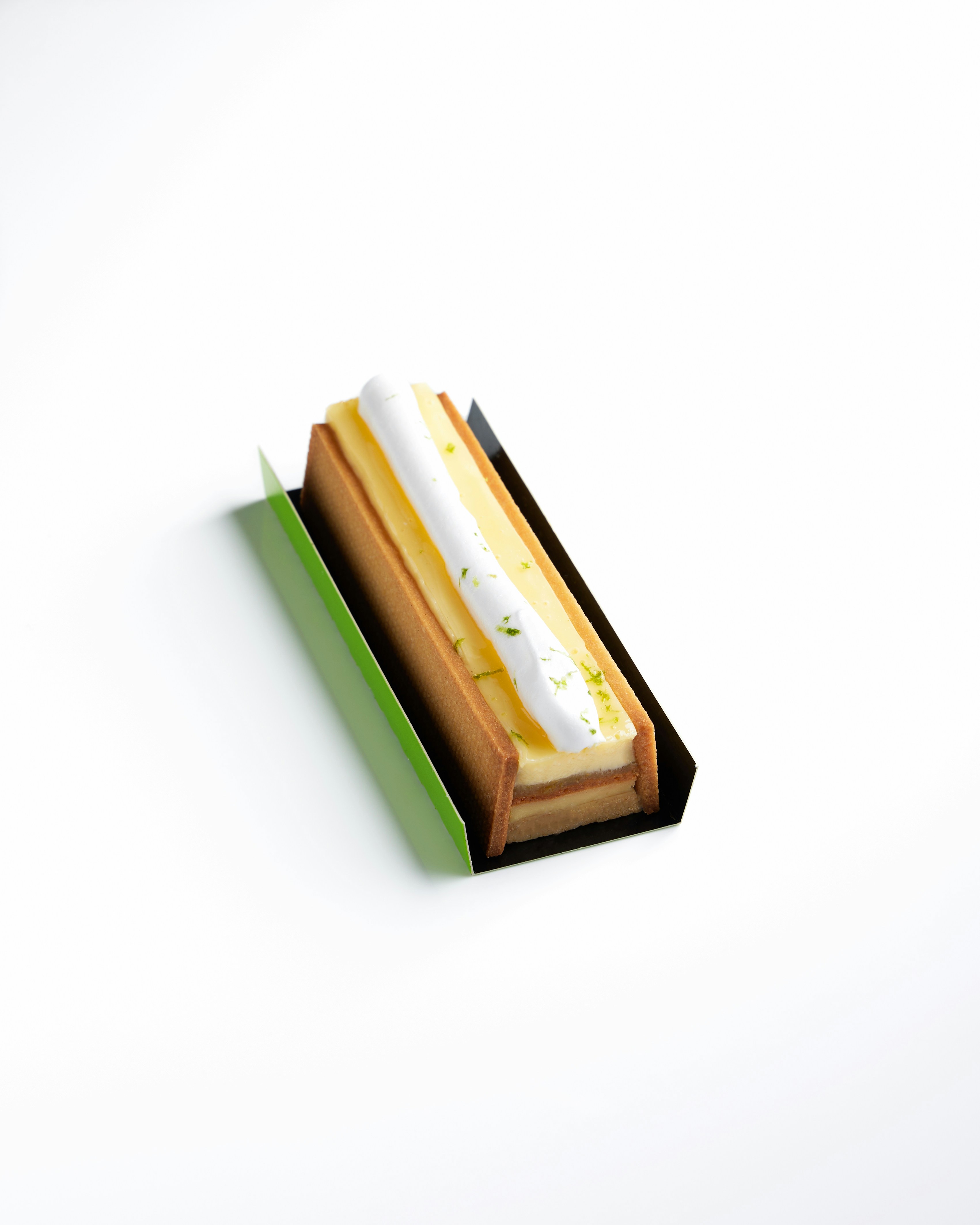 Un postre rectangular con relleno amarillo y crema blanca