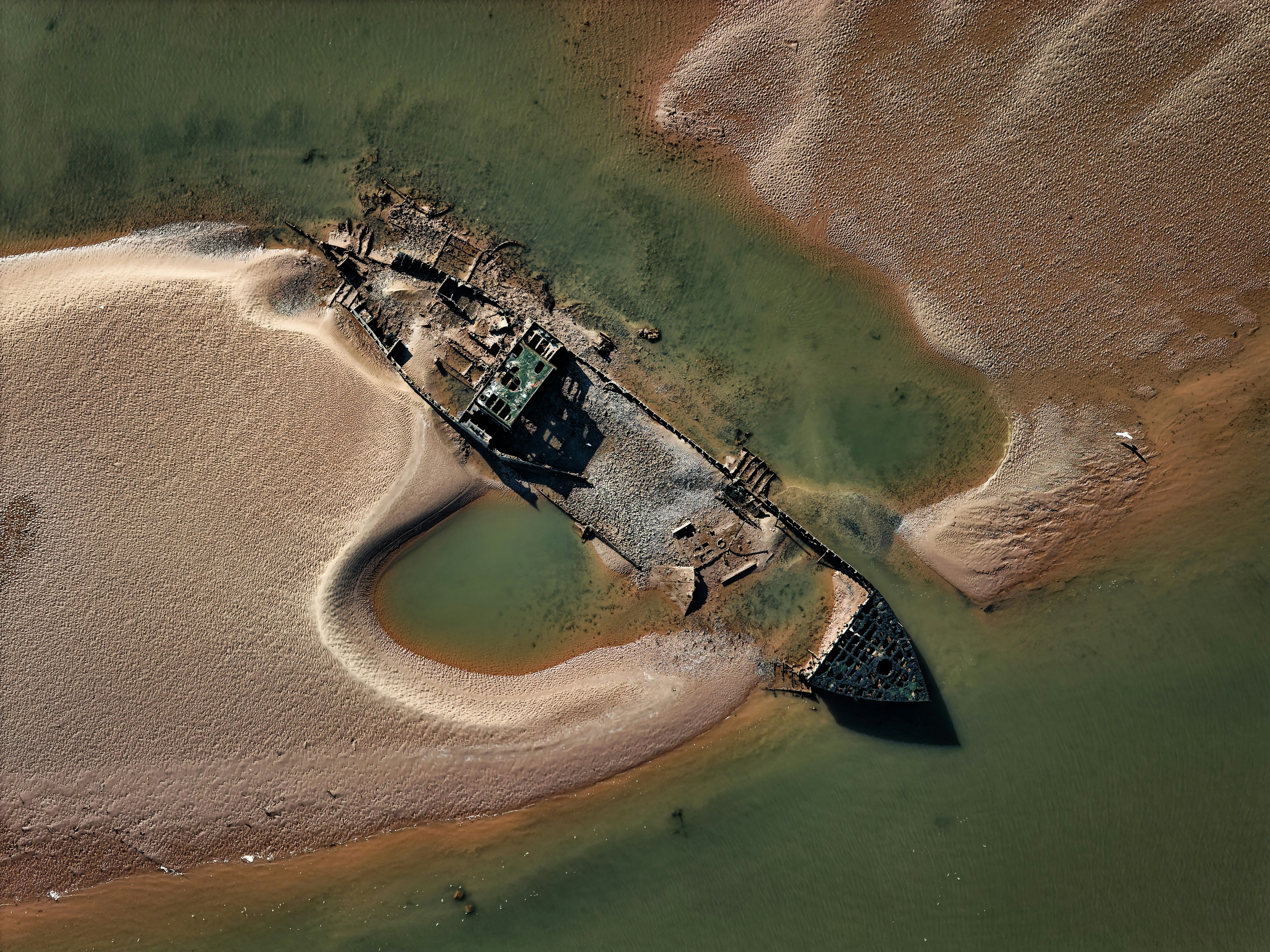 Épave coulée reposant sur un fond sablonneux à marée basse