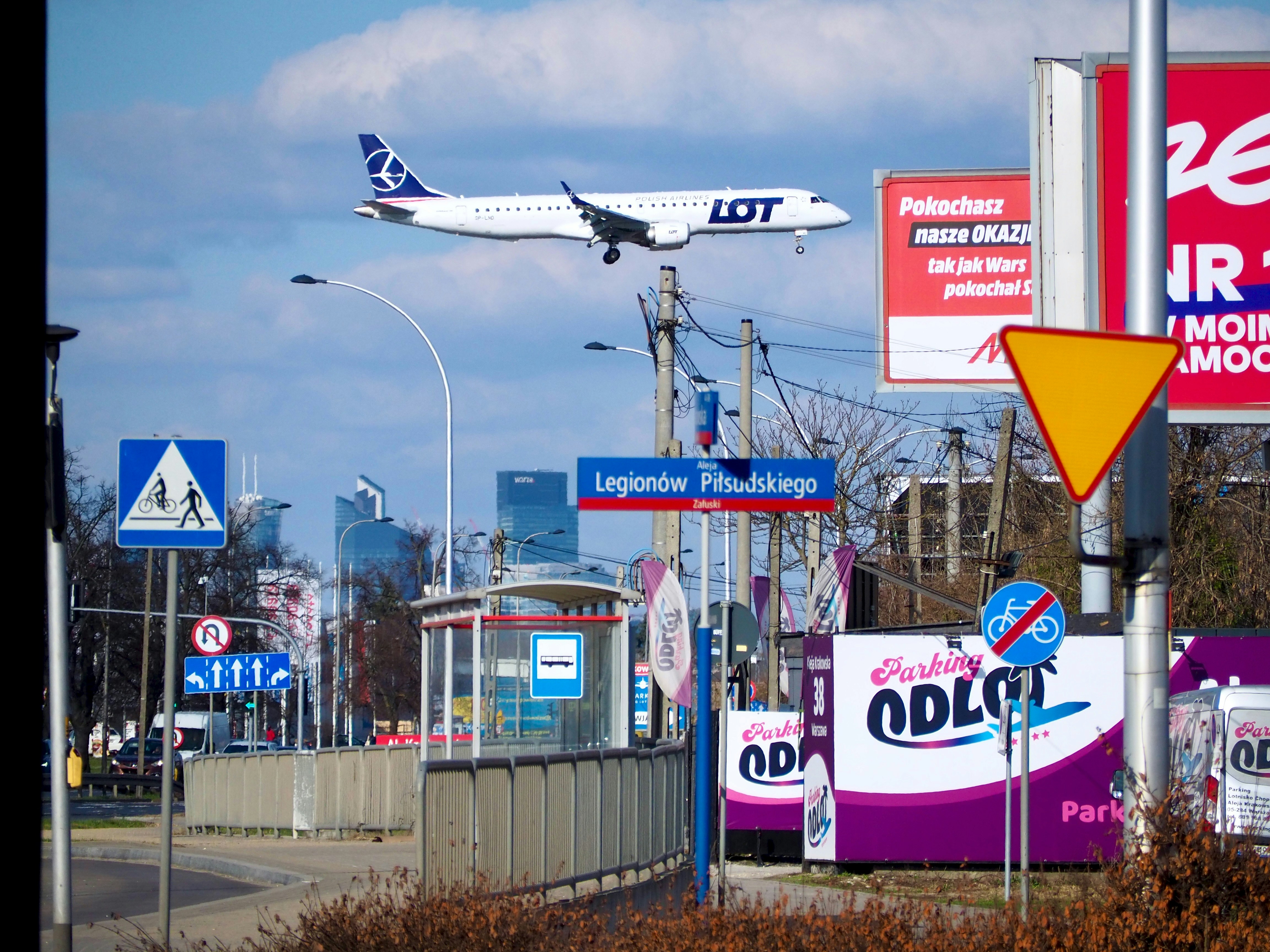 Airplane flying over city street with signs
