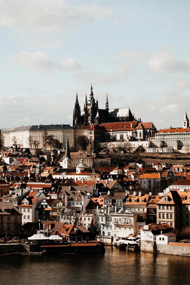 Prague Castle and St Vitus Cathedral above red rooftops beside the Vltava River