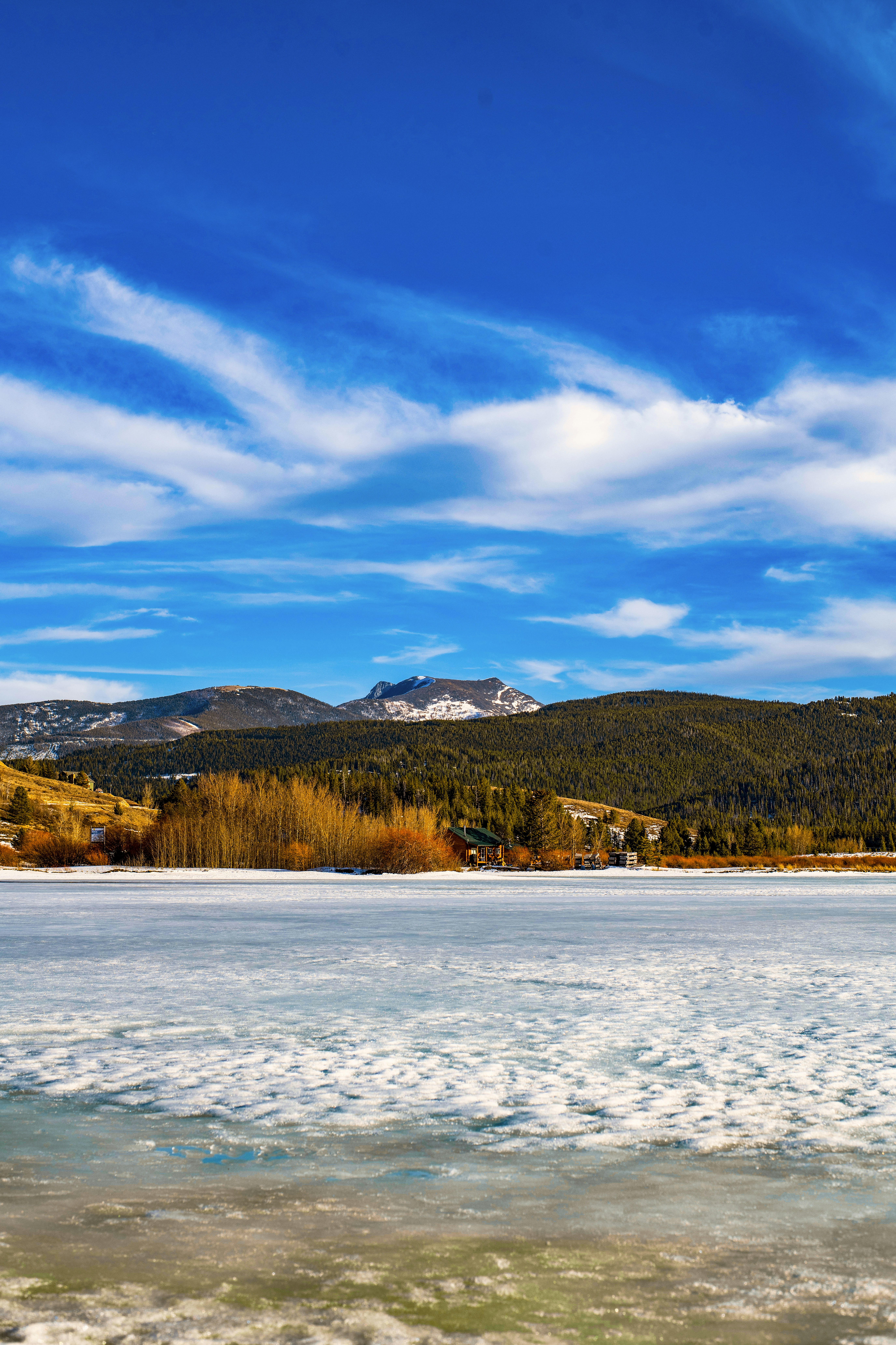 Lago ghiacciato con montagne e cielo azzurro