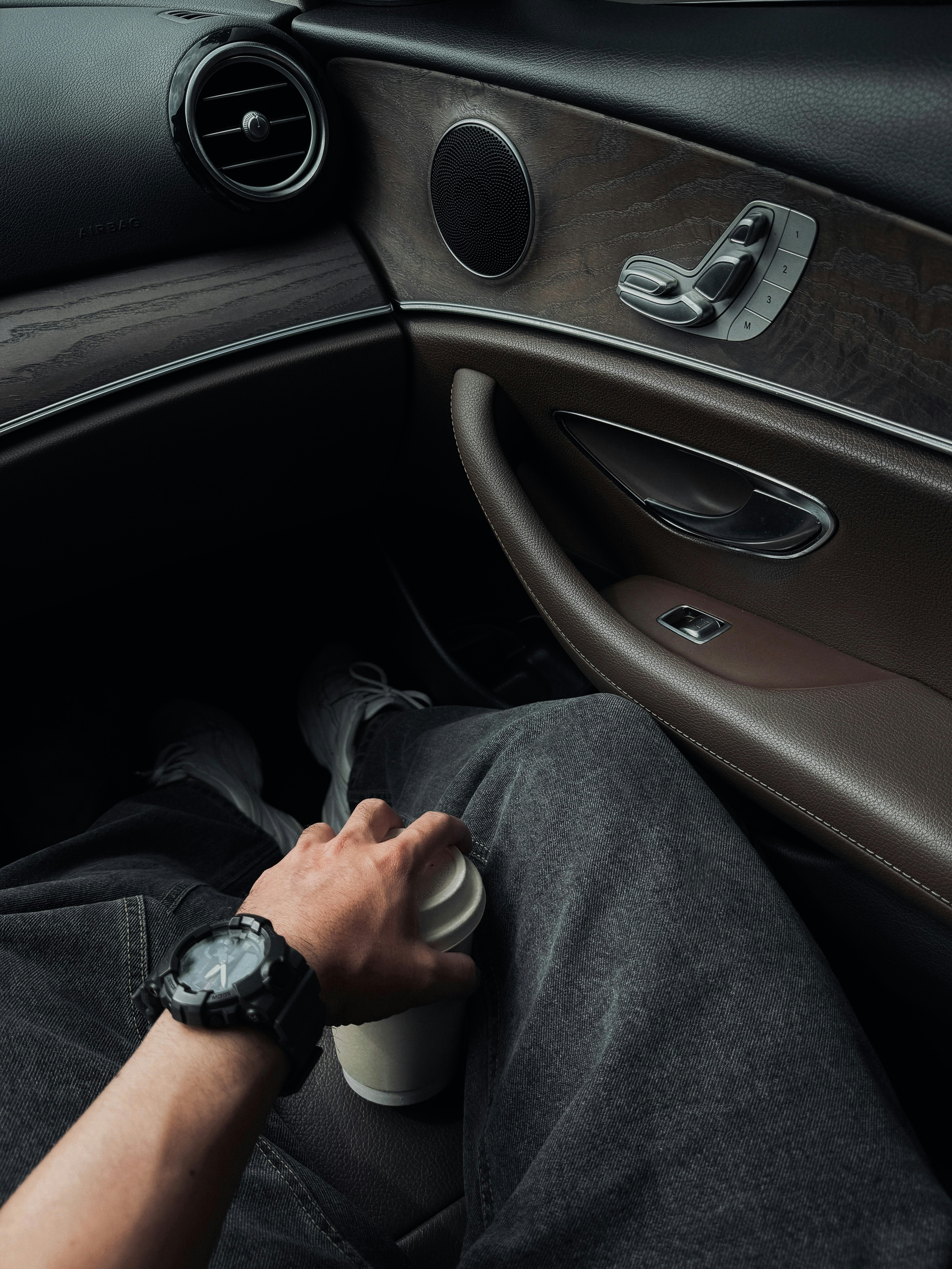 Persona che tiene una tazza di caffè dentro un'auto