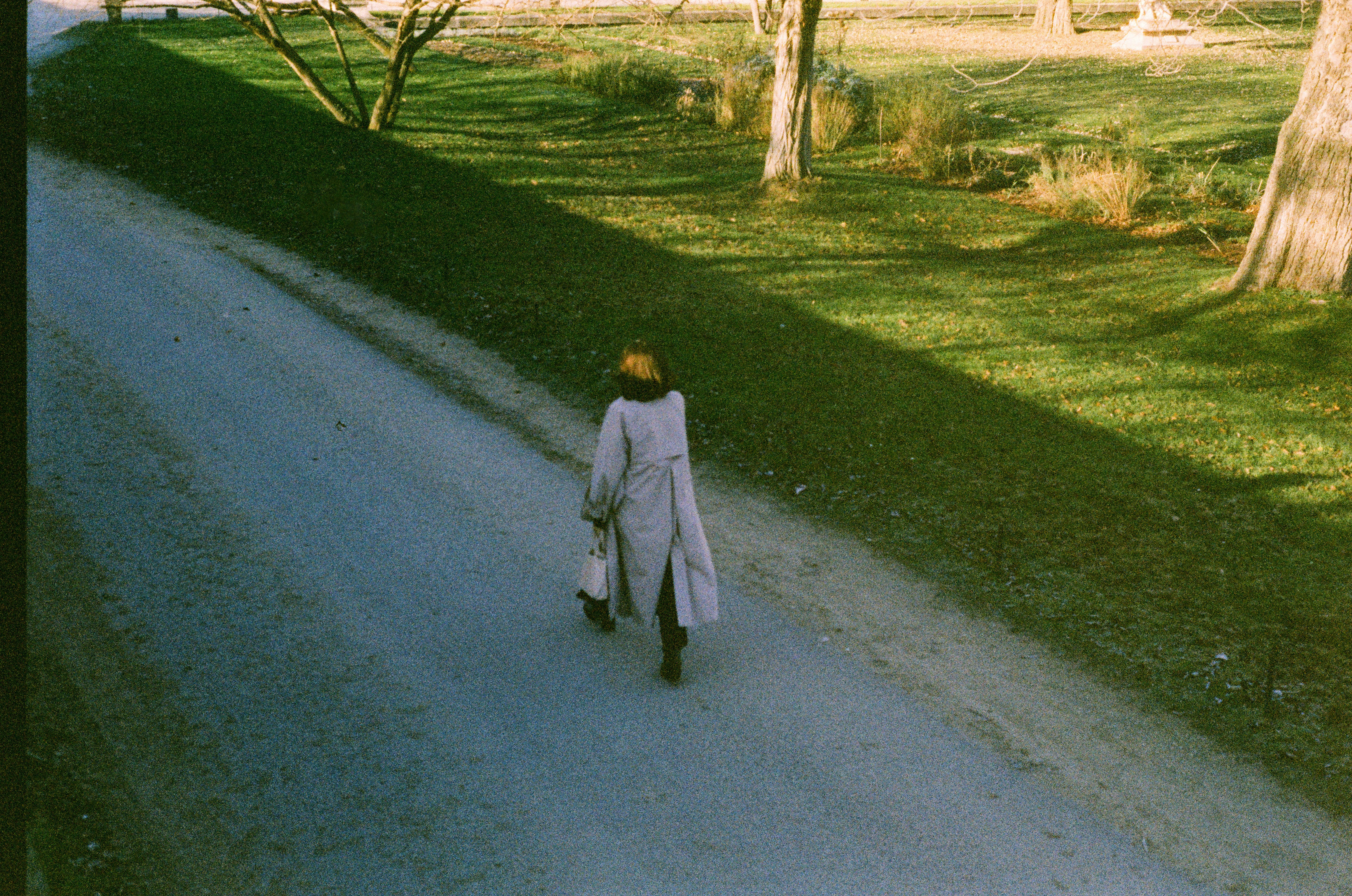 Una persona cammina lungo un sentiero di ghiaia in un parco.
