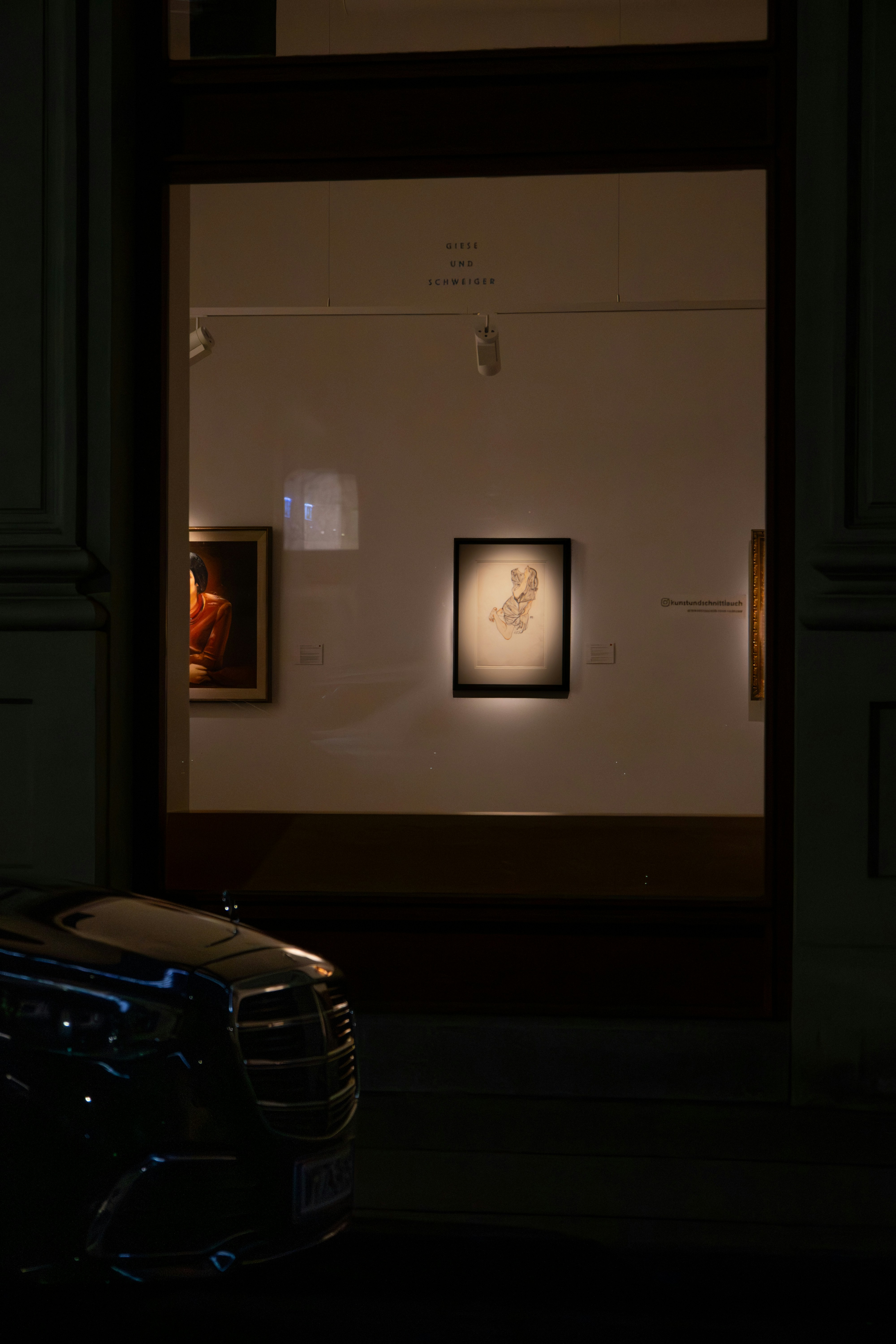Artwork displayed in a dimly lit gallery at night.